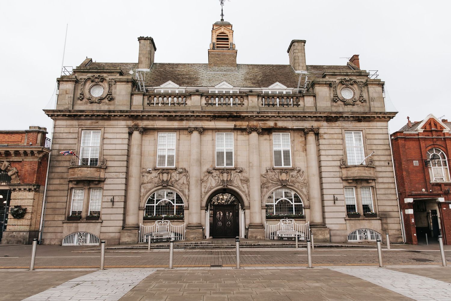 Historic stone town hall building with arched entrance, ornate facade, and clock tower in a cobblestone square.