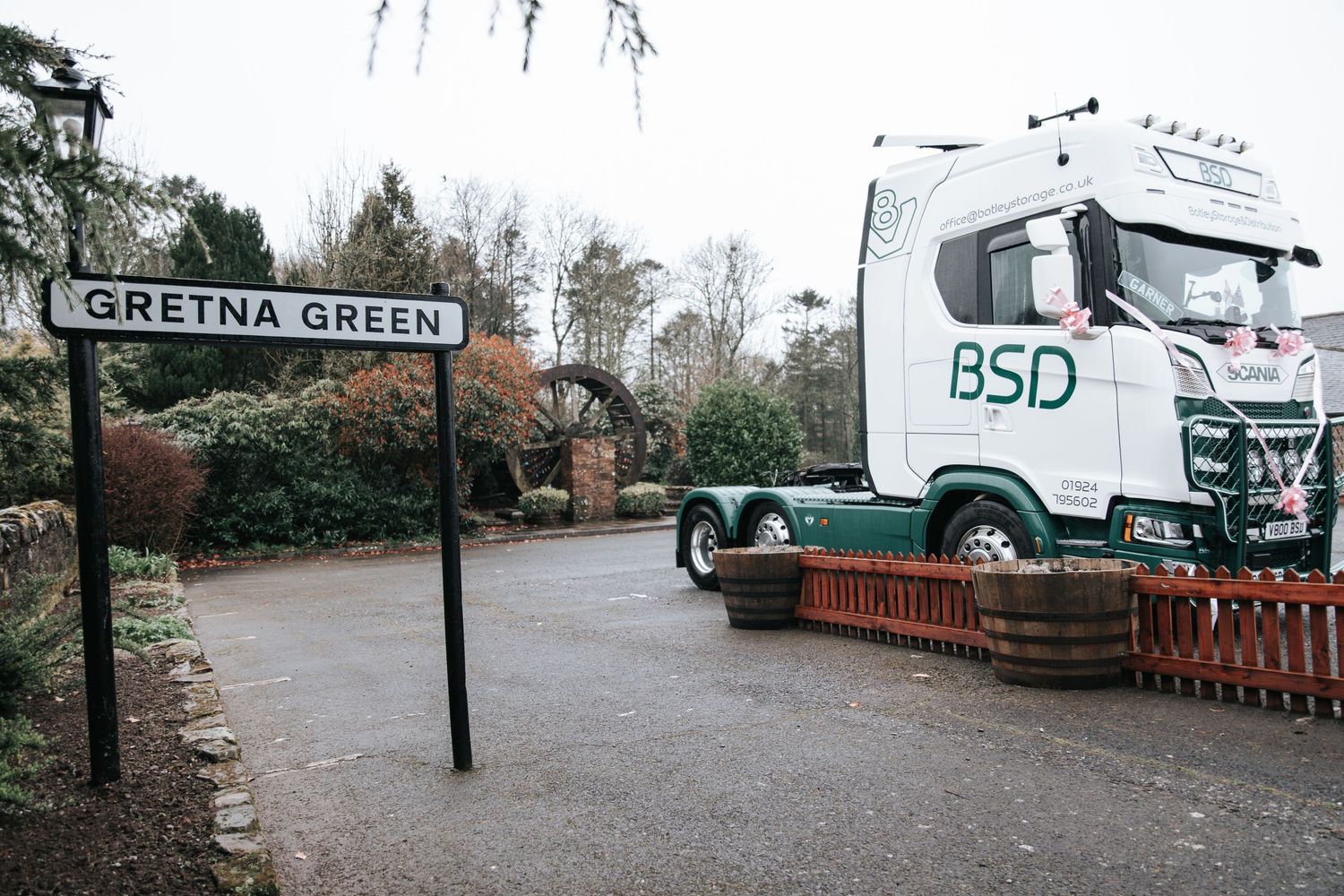 BSD logistics truck parked near Gretna Green road sign in Scotland on a cloudy winter day.
