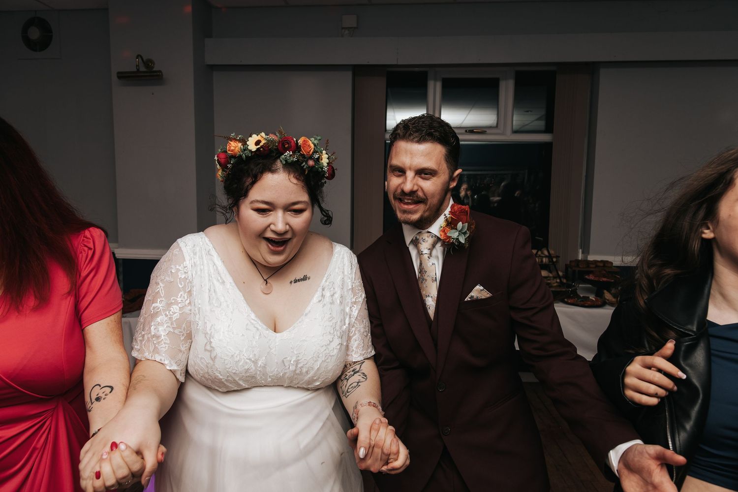 A couple shares an intimate moment during their wedding celebration, with guests visible in the background.