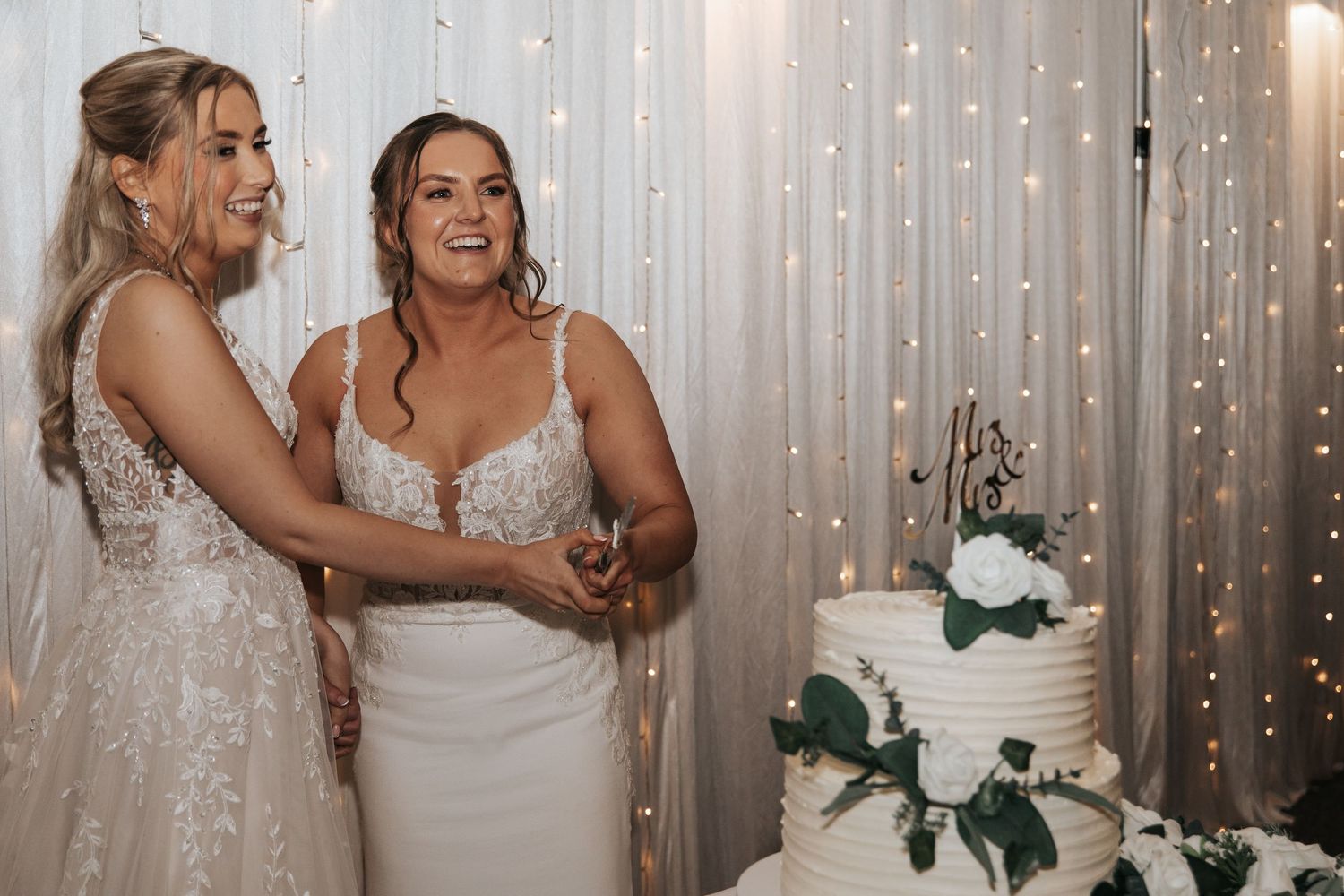 Wedding party poses against sparkly backdrop with string lights.