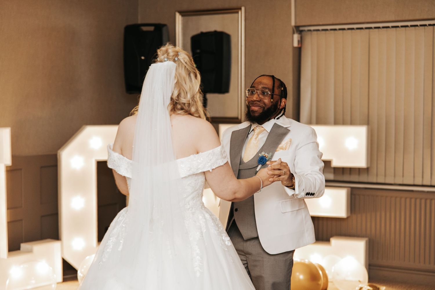 Wedding celebration with guests dancing and interacting in a dimly lit reception venue.
