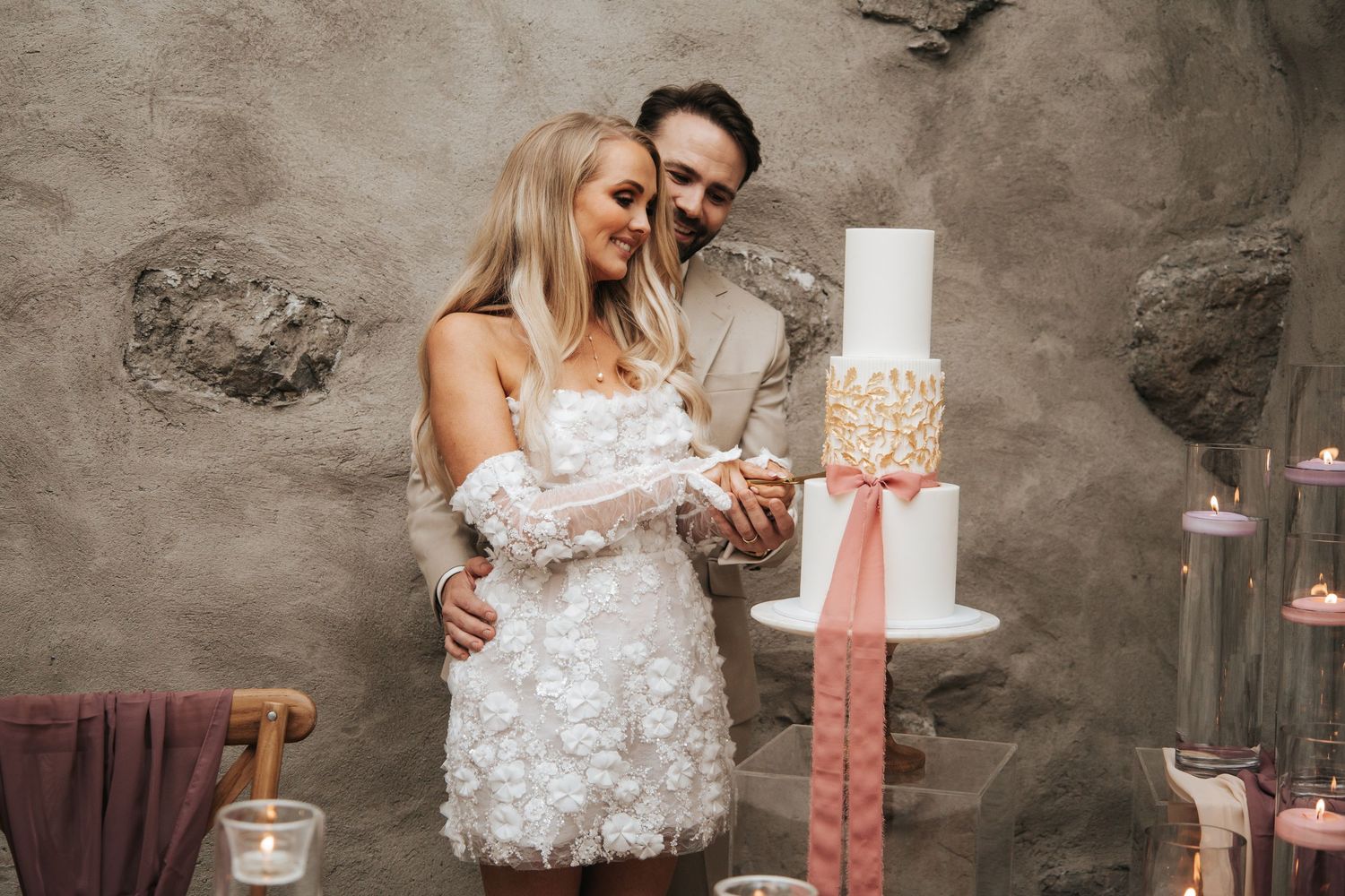 Romantic wedding portraits with soft lighting and floral decor against concrete walls.