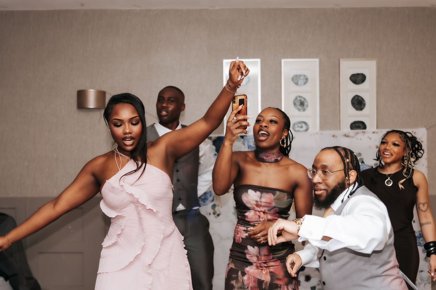 A group of wedding guests dance and celebrate together at a lively reception party.