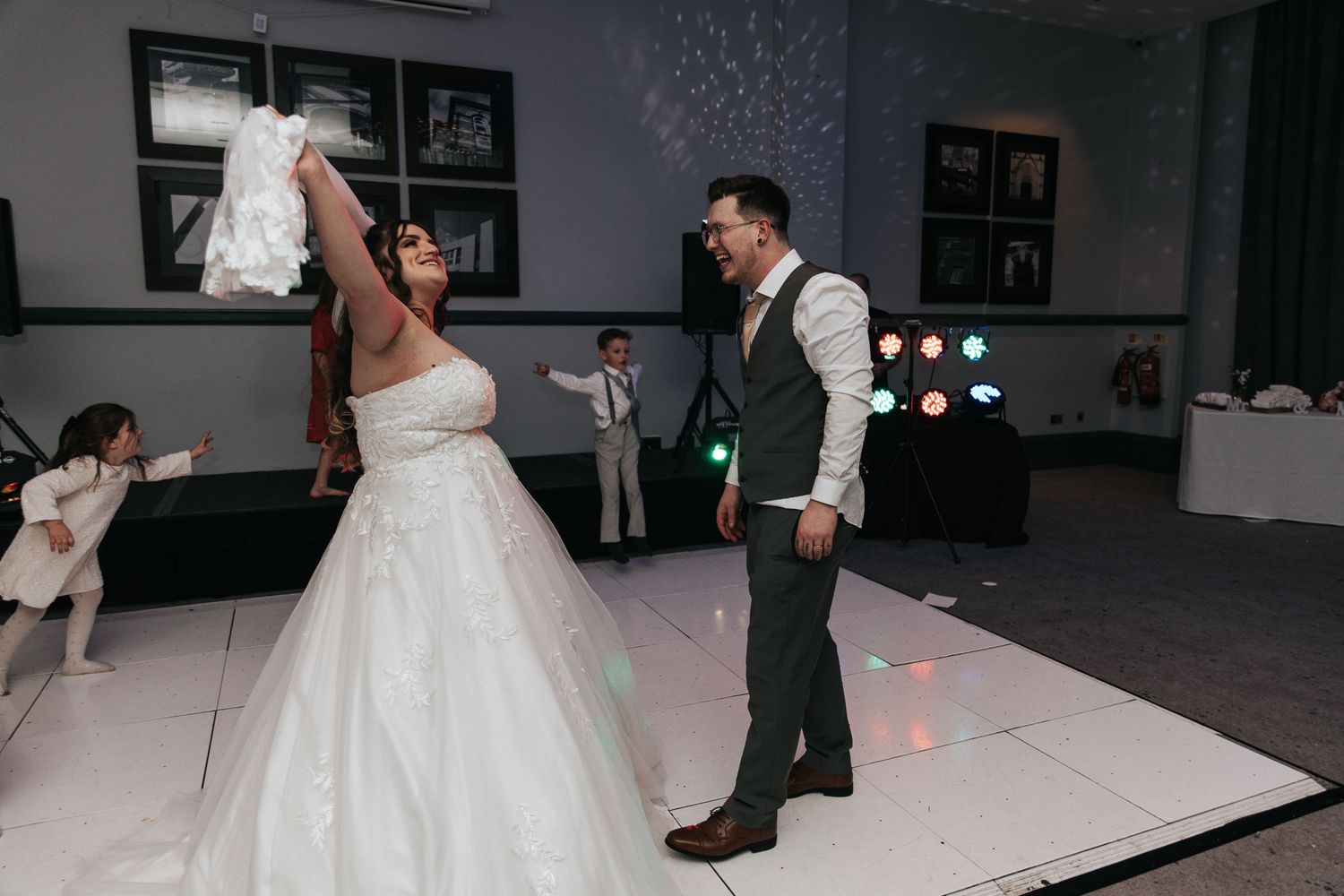 A couple shares a romantic dance moment on a white dance floor at their wedding reception.