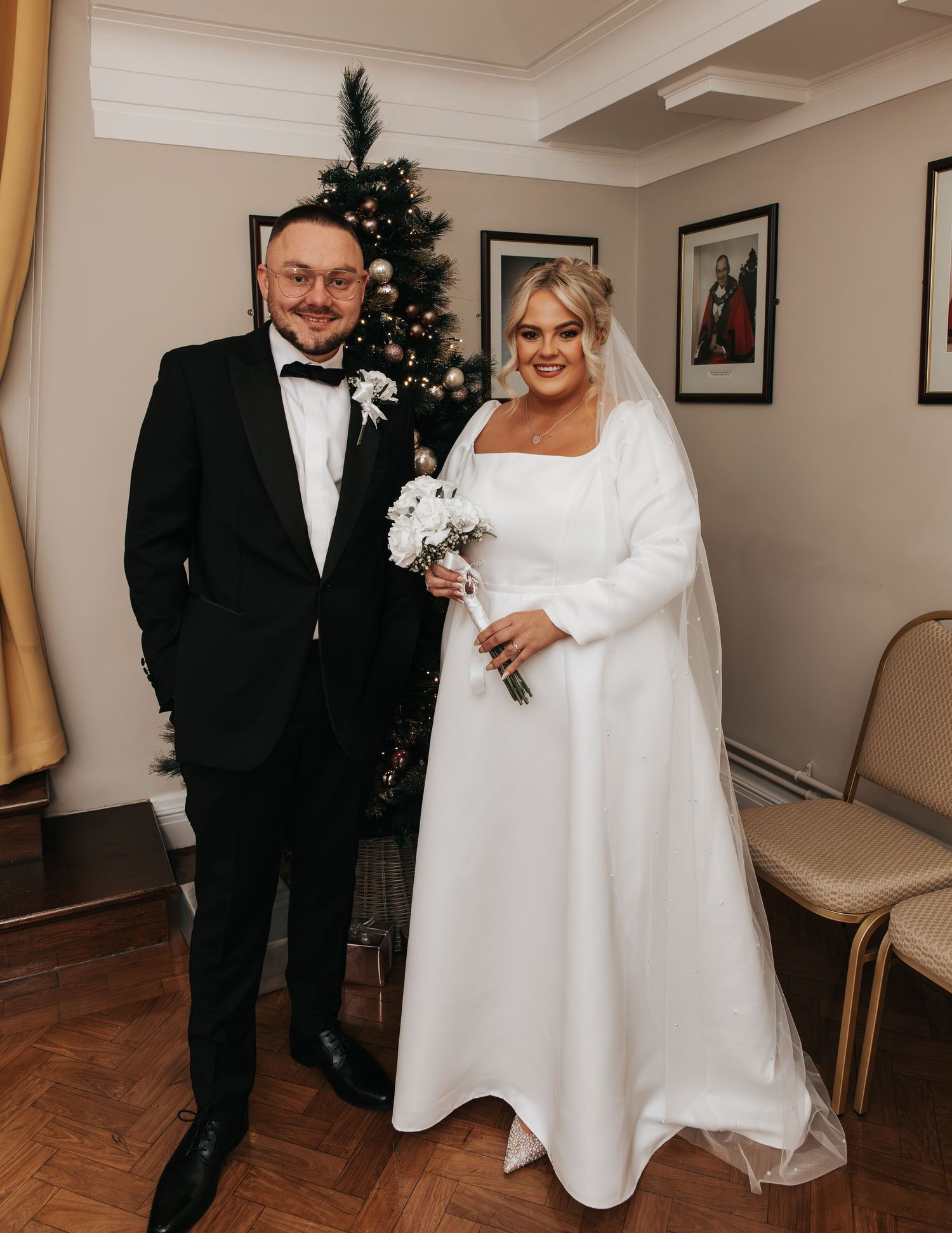 Wedding ceremony in elegant indoor venue with Christmas tree and hardwood floors.