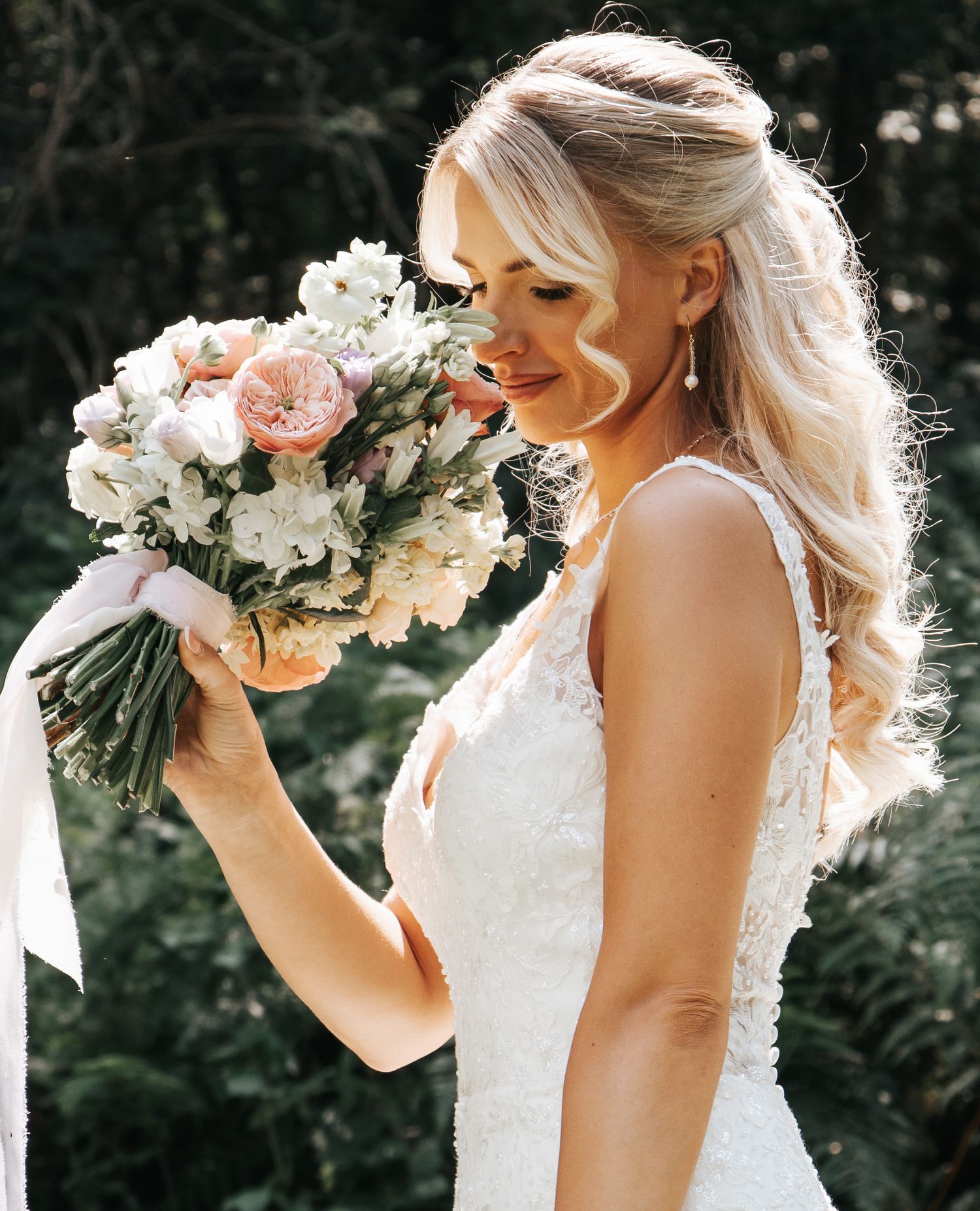 Side profile of wedding dress with delicate bouquet featuring pink and white blooms.