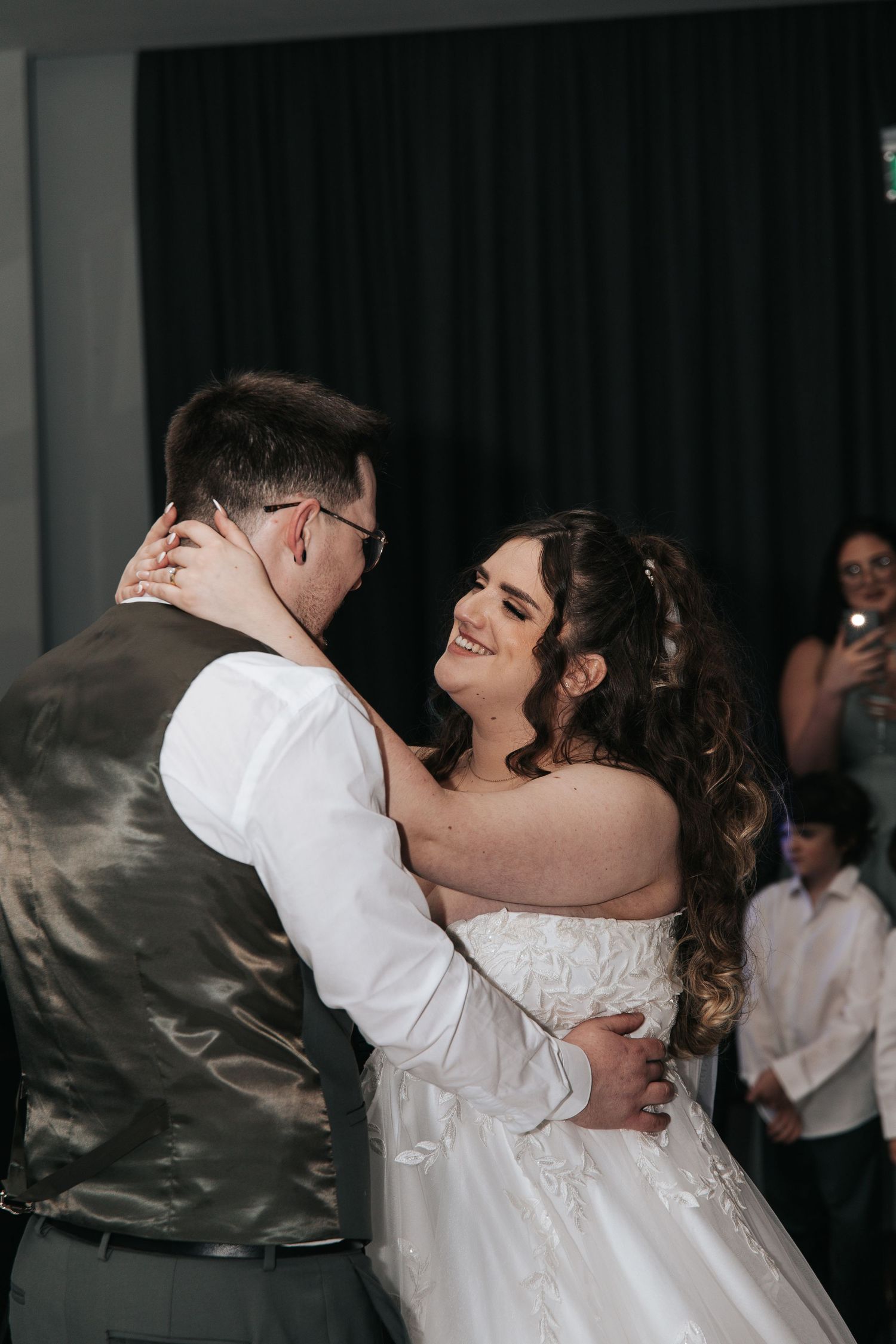 A couple shares an intimate dance at their wedding reception, with the bride wearing a beautiful white gown.