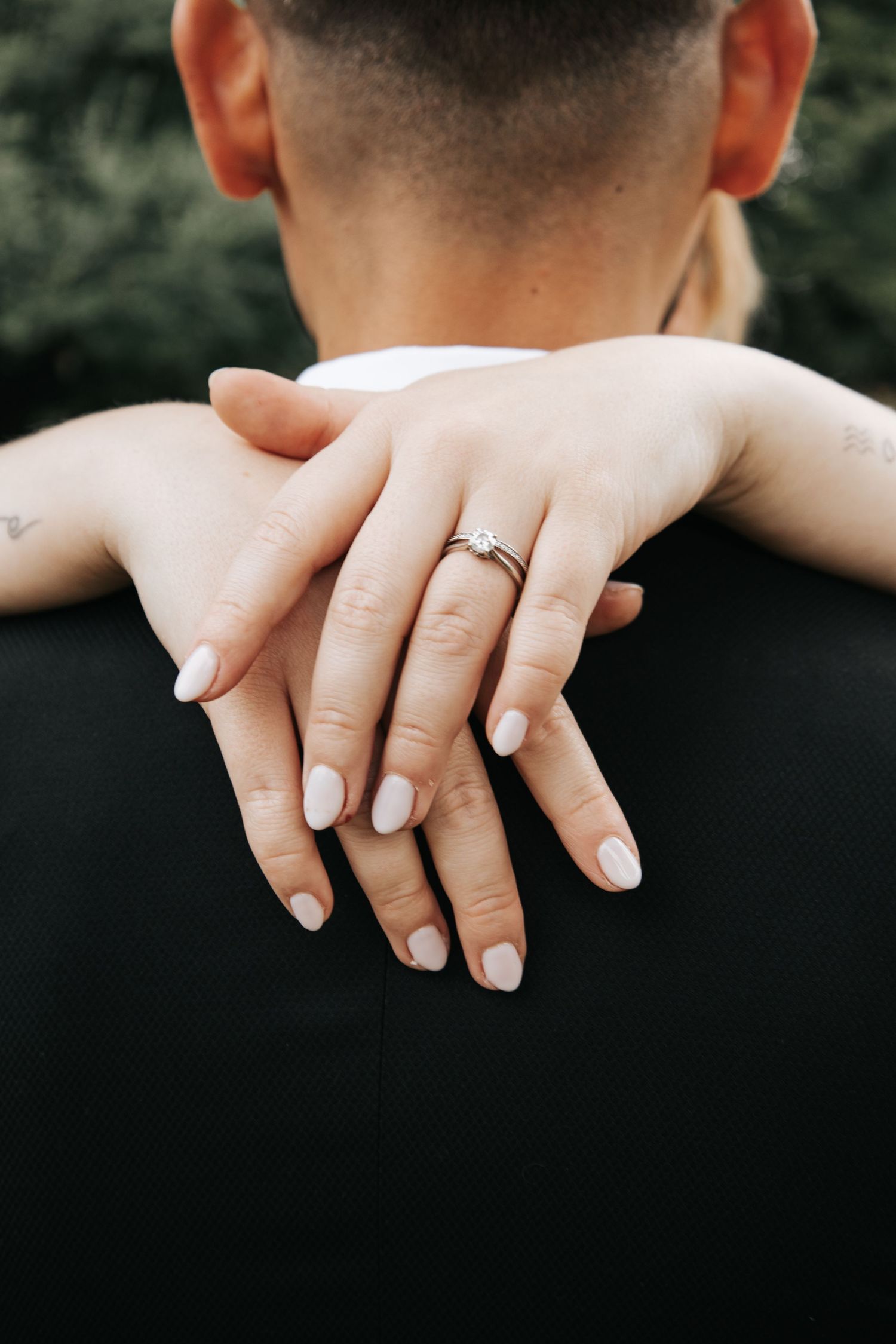 Close-up of manicured hands showing off a wedding ring.