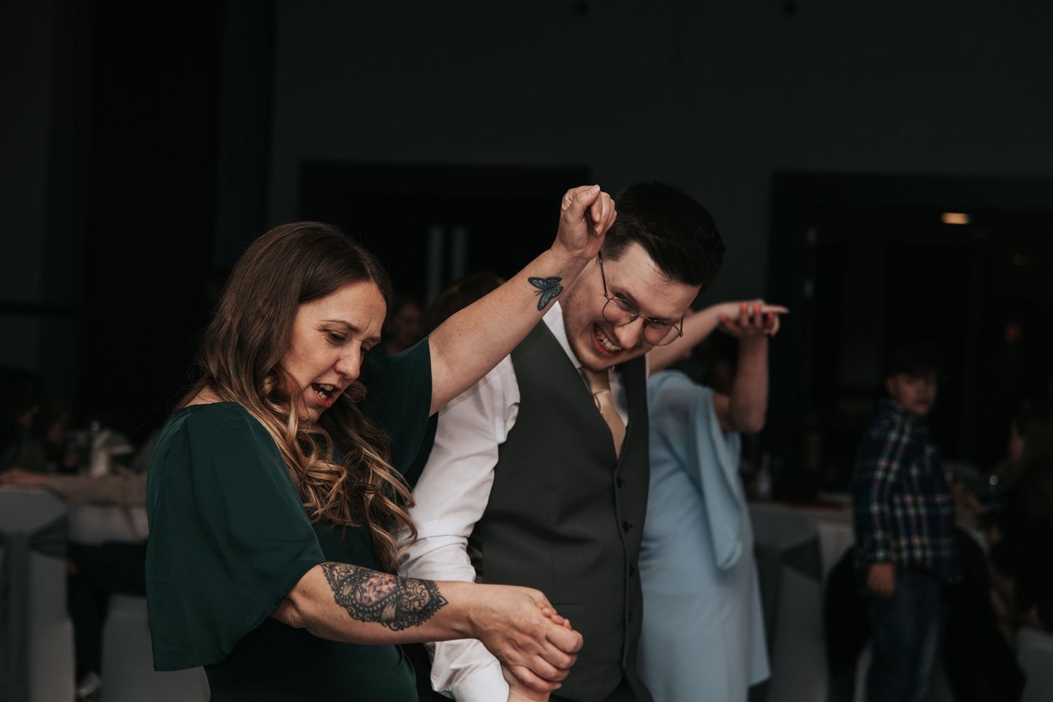 A couple dancing together in a romantic embrace during a dimly lit dance floor moment.