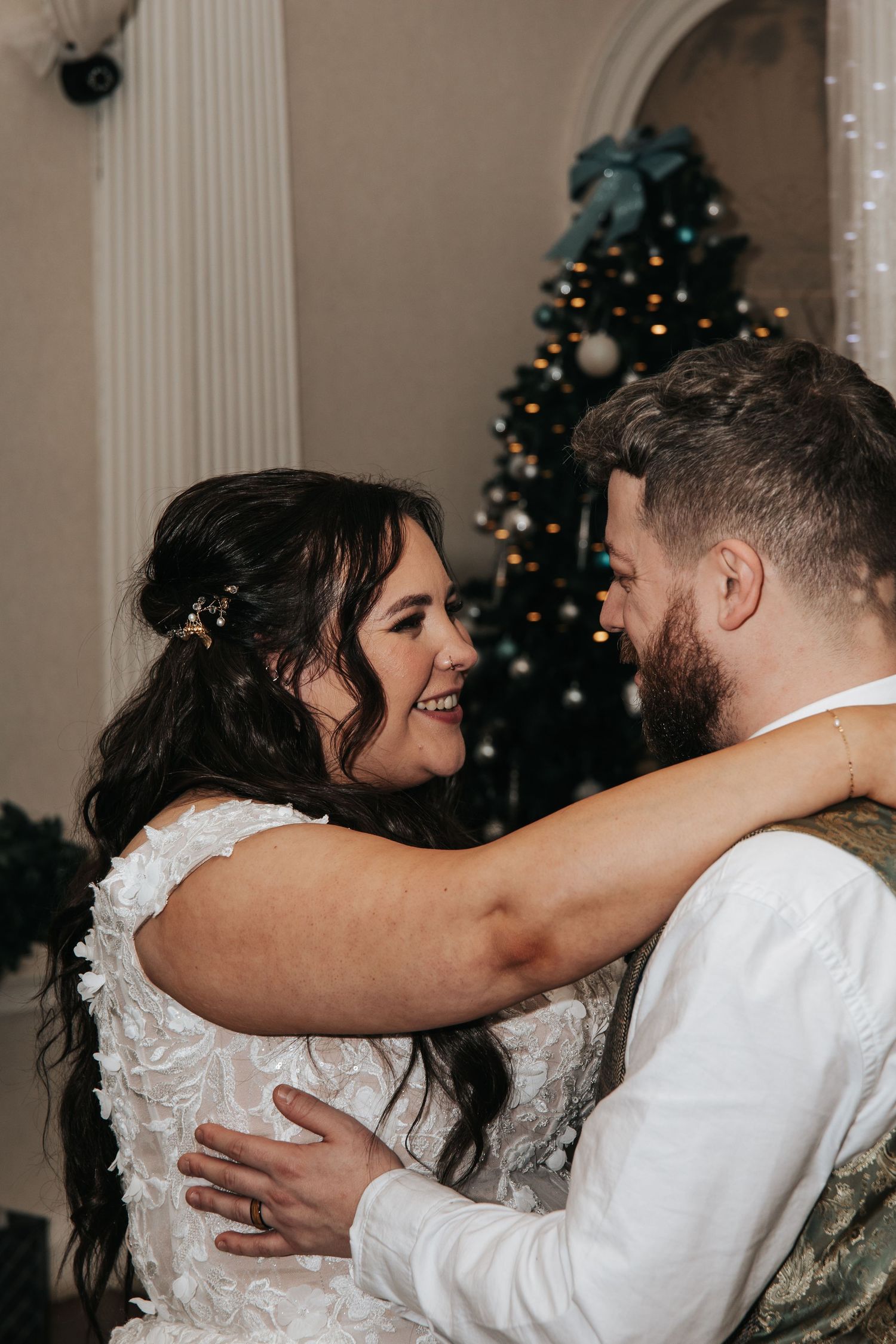 Intimate wedding moment captured in front of a decorated Christmas tree.