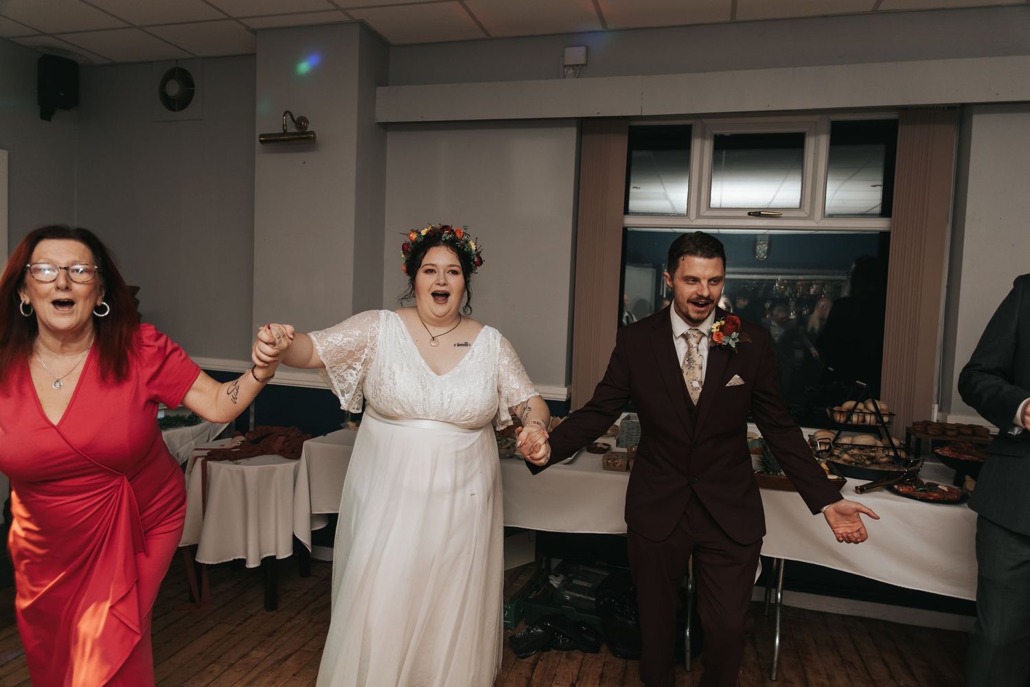Wedding party dances and celebrates during a lively reception in an indoor venue.