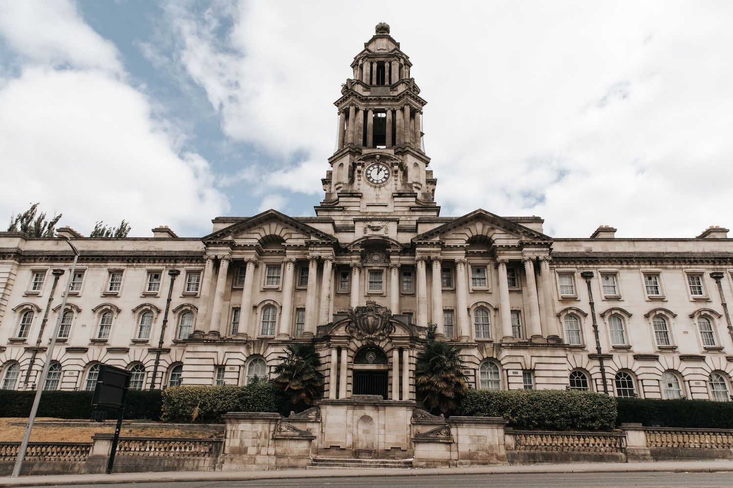 Grand neoclassical government building with ornate clock tower against cloudy sky in London.