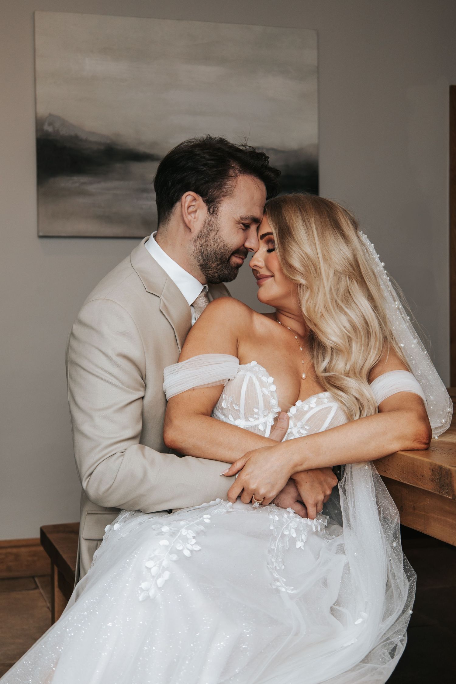 Wedding couple embraces lovingly at a rustic wooden table.