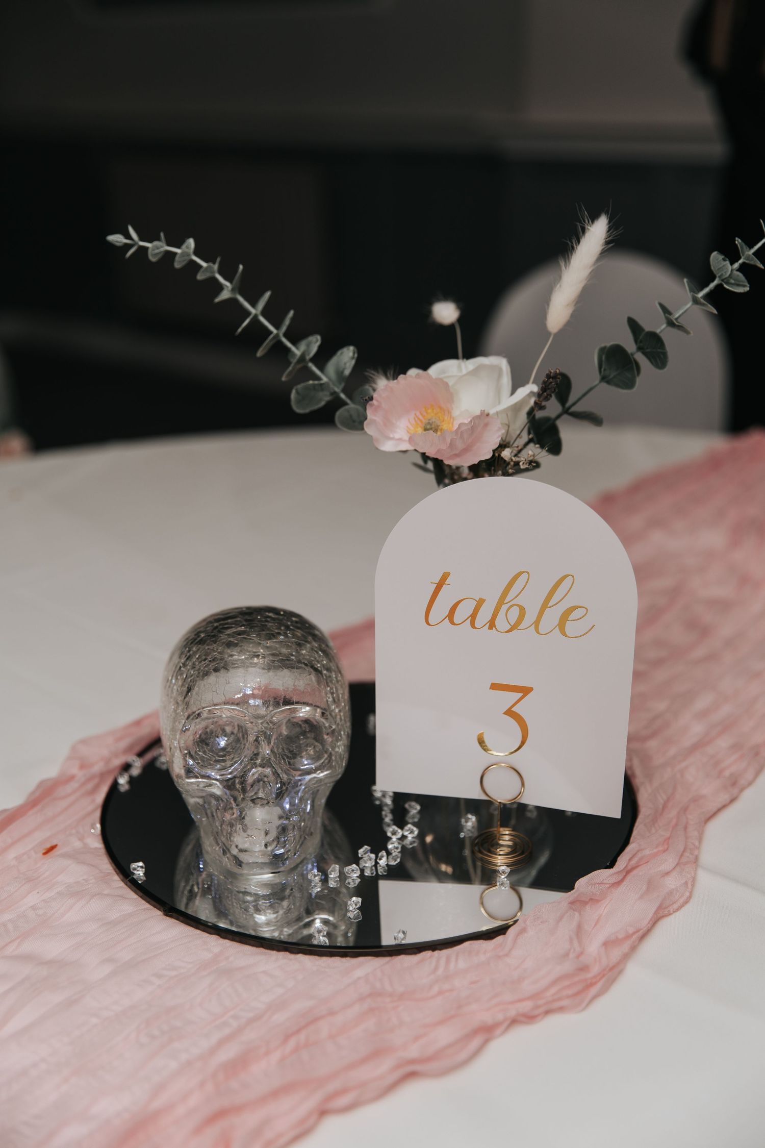 Elegant wedding table 3 centerpiece with crystal skull, pink runner, mirror tray, and floral arrangement with eucalyptus.