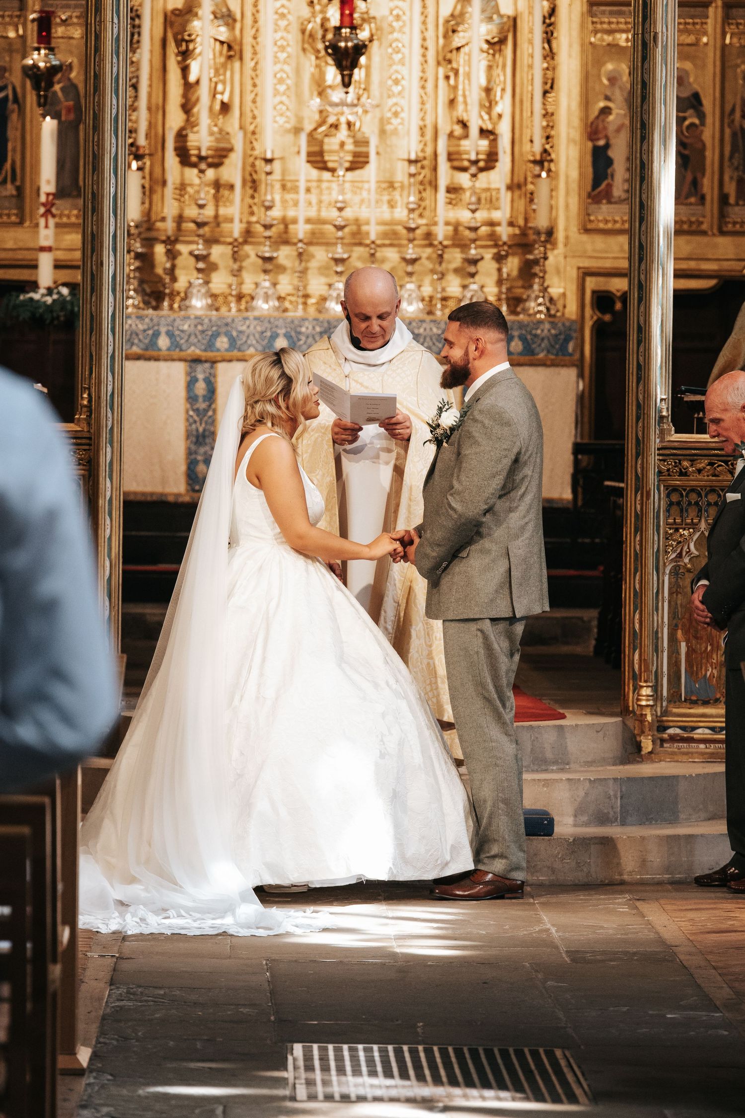 Bride and groom exchange vows at ornate church altar, officiant reading ceremony script during elegant wedding.