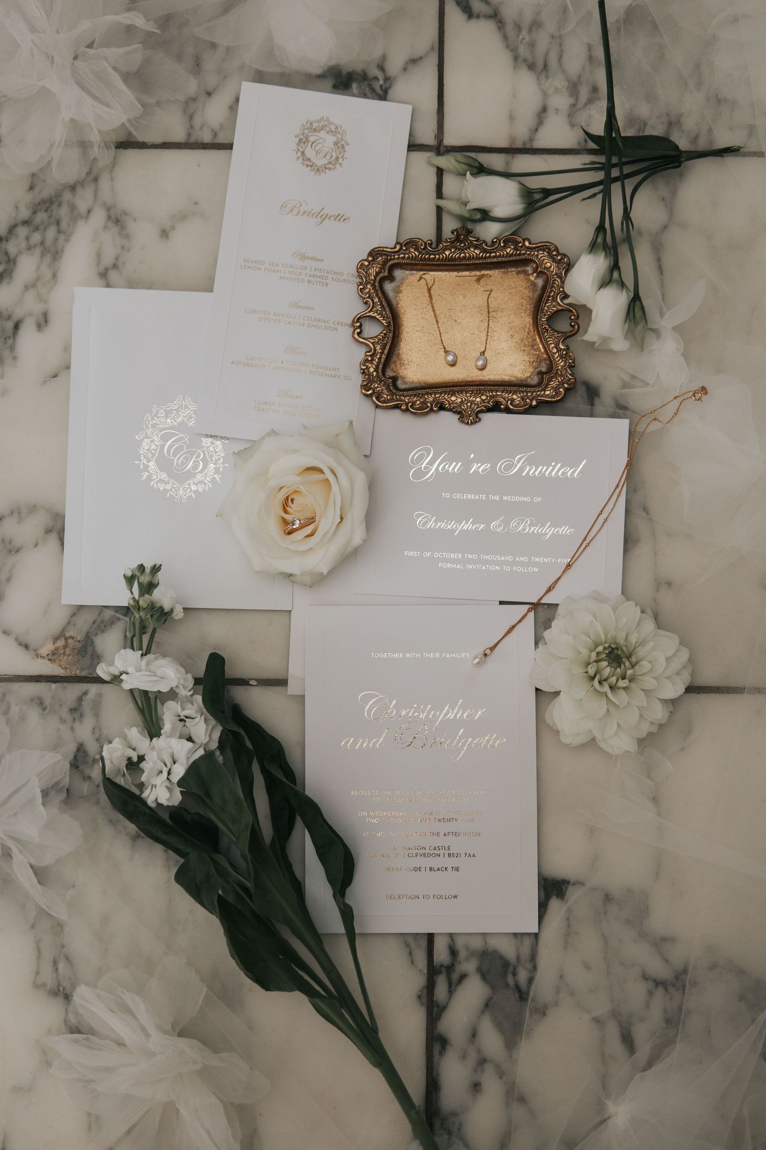 Wedding invitation suite with white flowers and vintage frame on marble background.