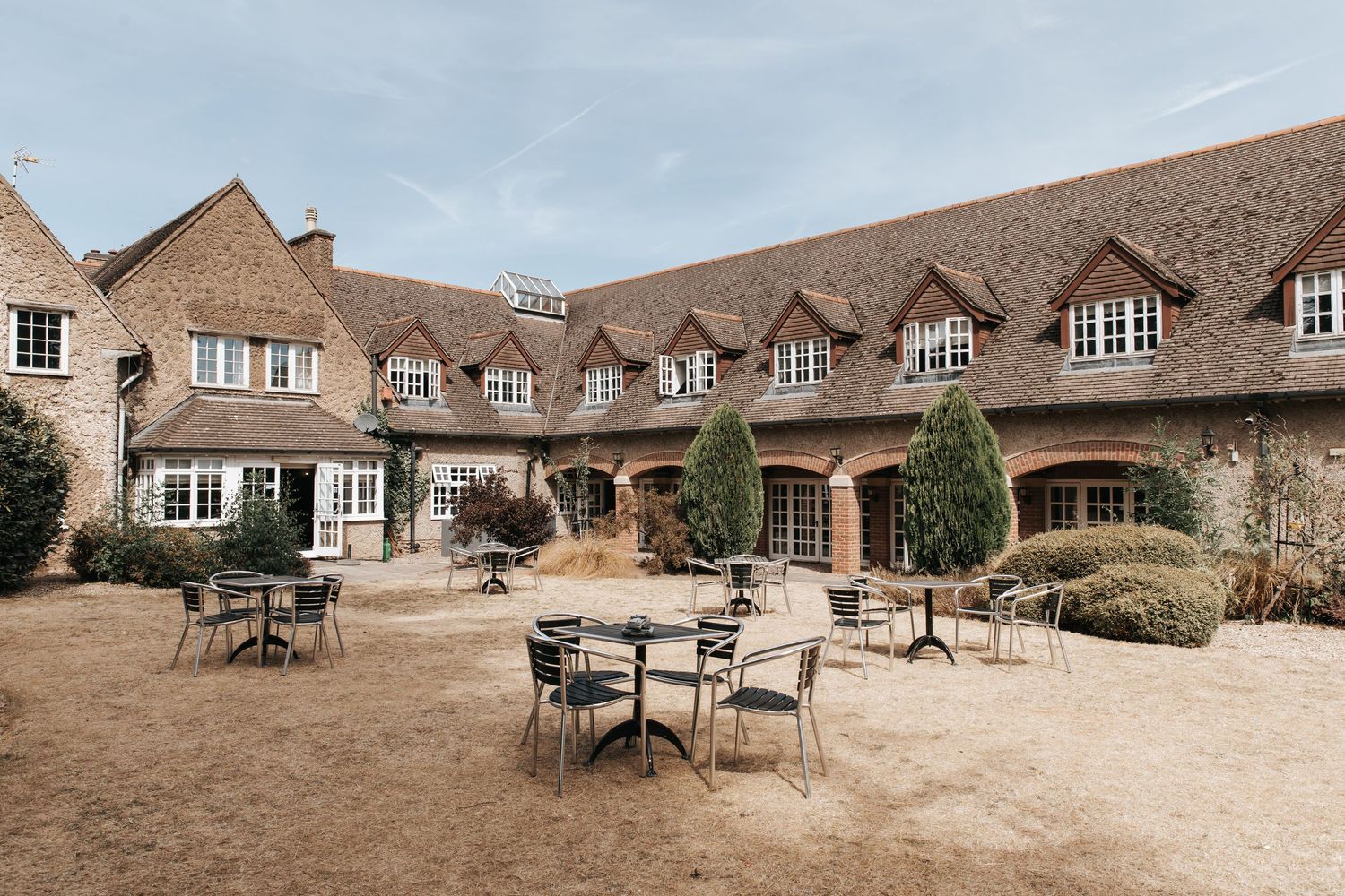 Stone country house hotel with outdoor courtyard seating area, featuring rustic architecture and manicured grounds.