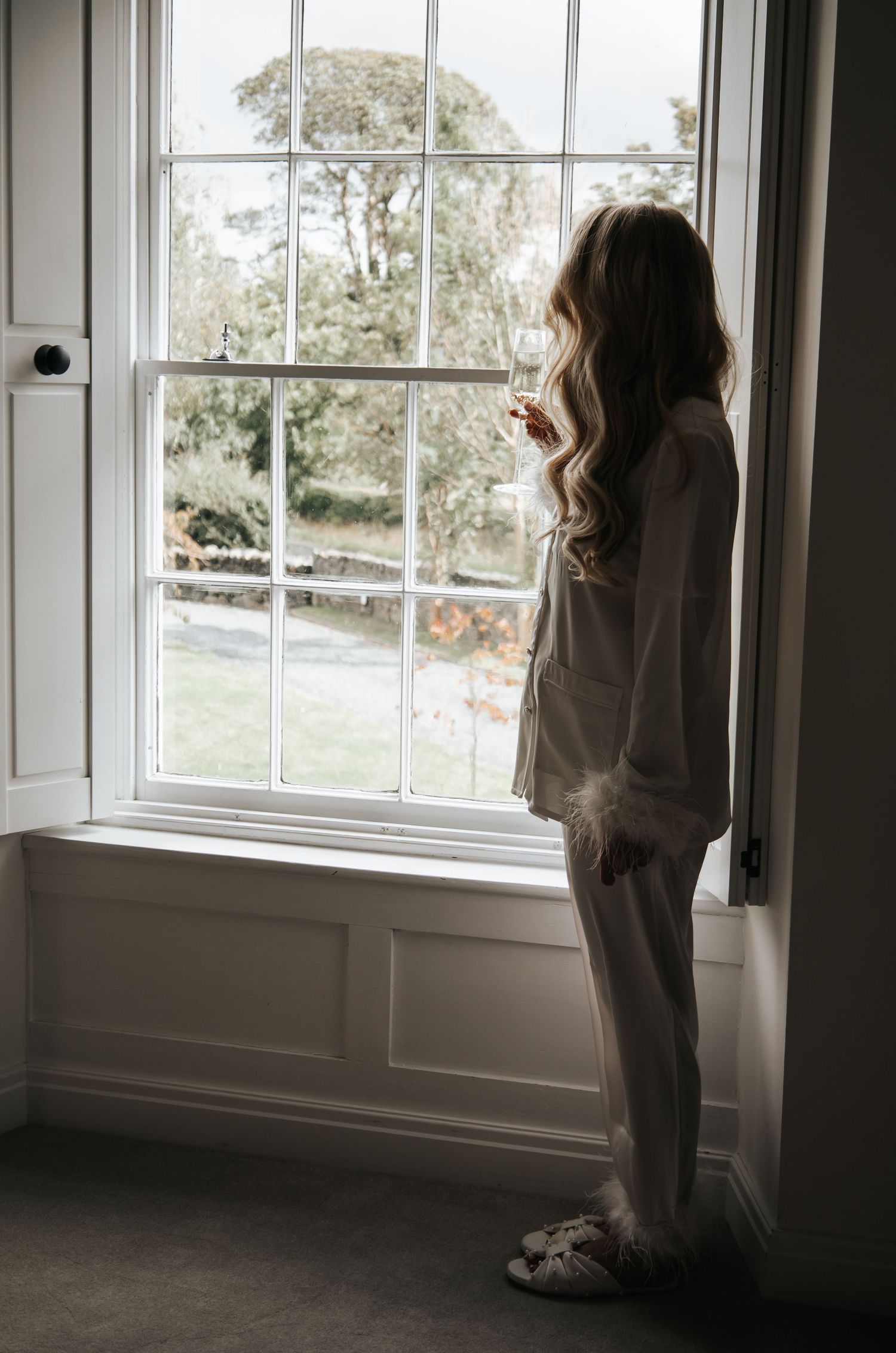 Person in comfortable clothing looking thoughtfully out large window.
