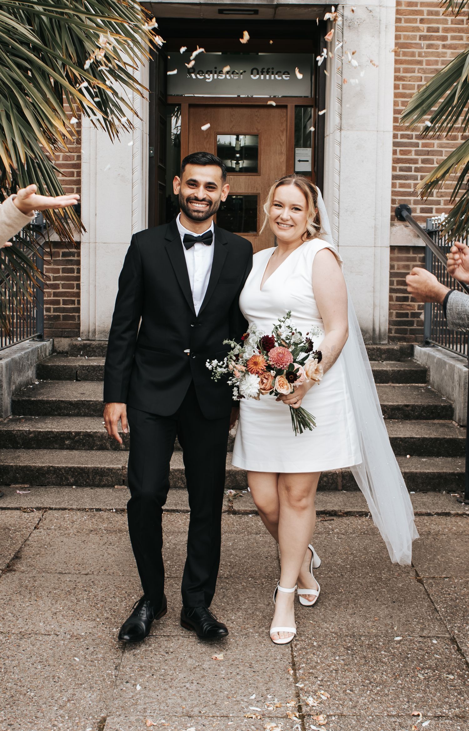 Happy couple posing for wedding photos outside a registry office.