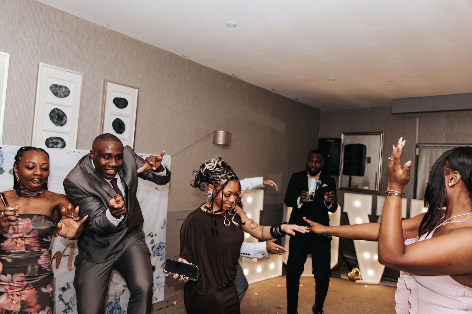 Wedding guests dancing together on a dimly lit dance floor during a reception celebration.