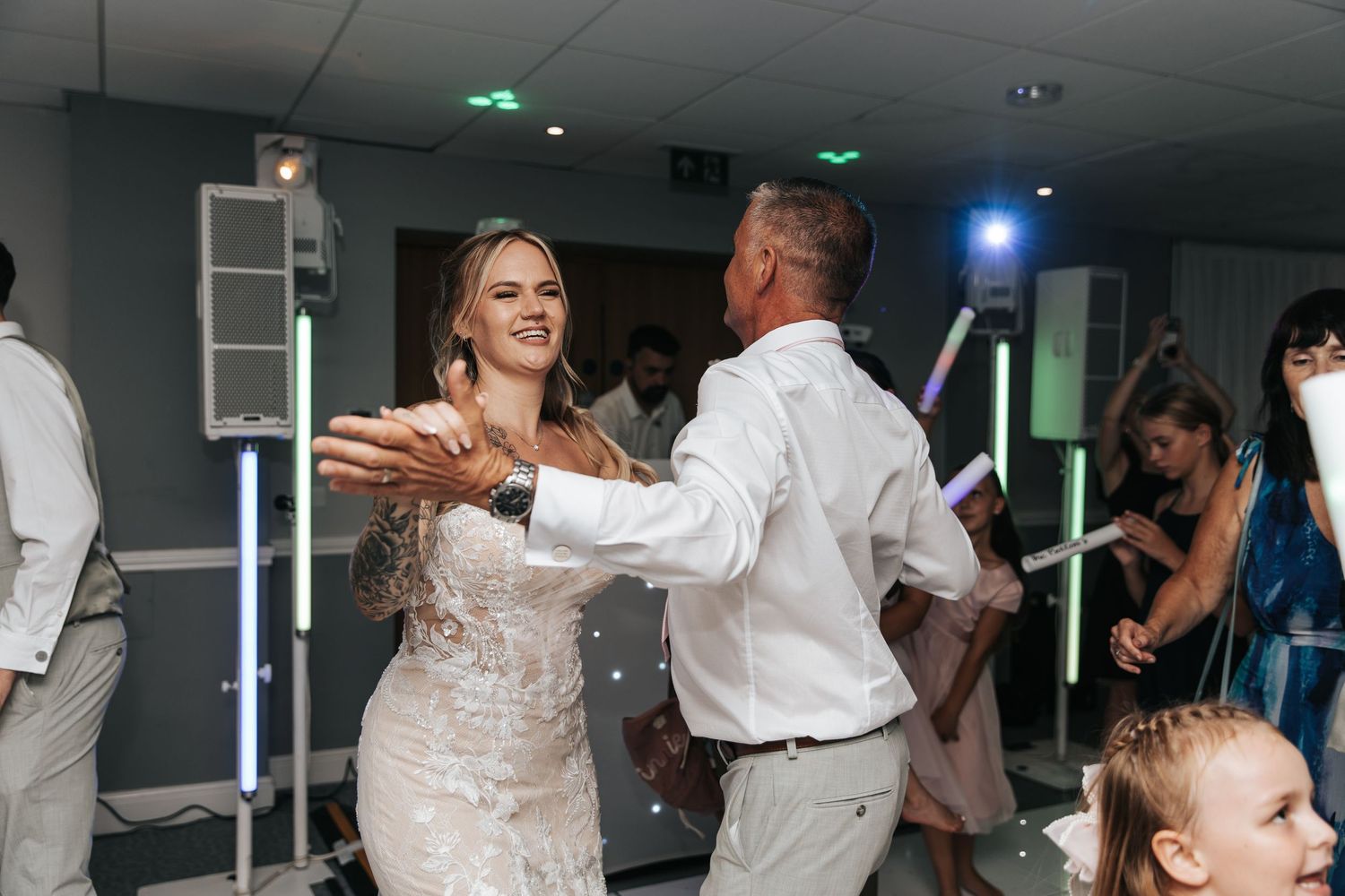 Bride and groom share a joyful first dance at their wedding reception surrounded by guests.