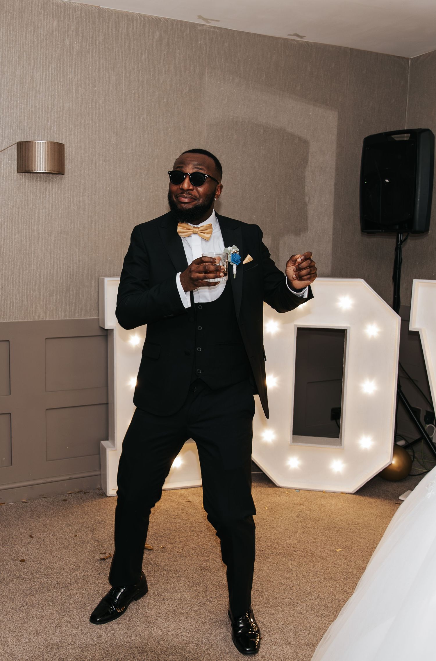 Wedding reception dance floor scene with illuminated letters and guests dancing in formal attire.