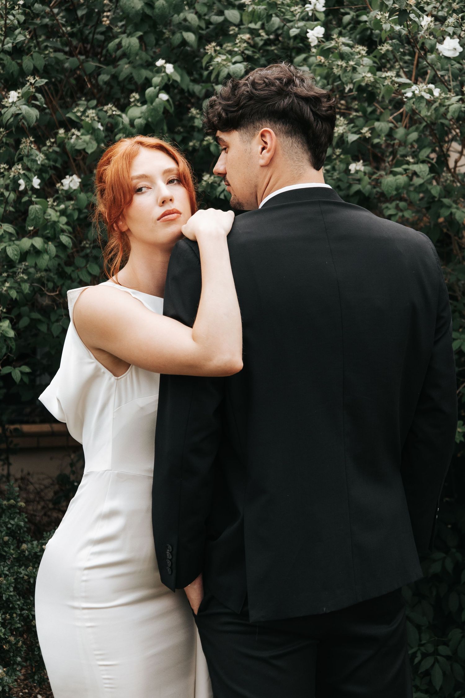 Wedding portraits against lush garden backdrop showing intimate poses in black and white attire.