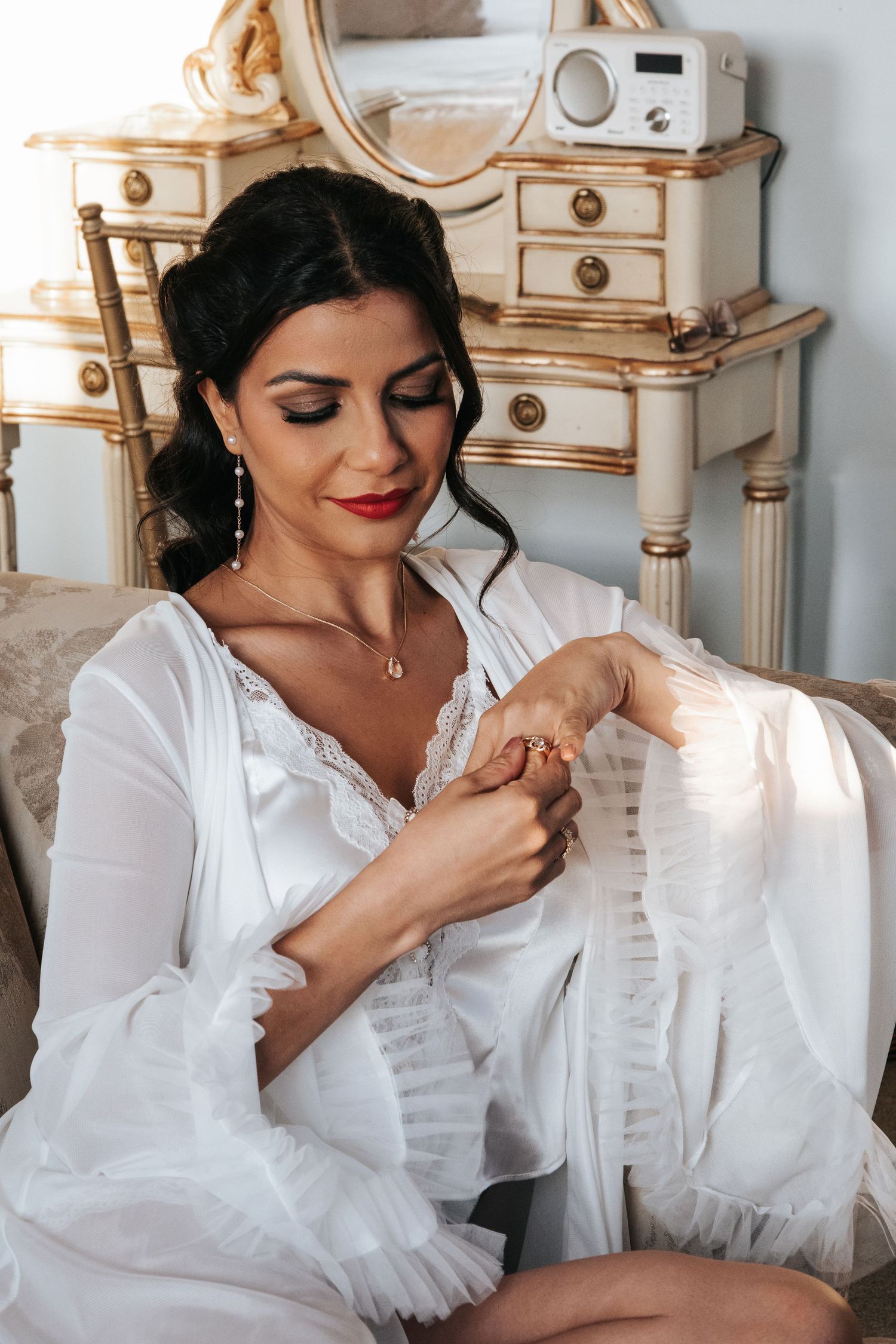 Elegant bridal portrait in white lace dress against vintage furniture backdrop.