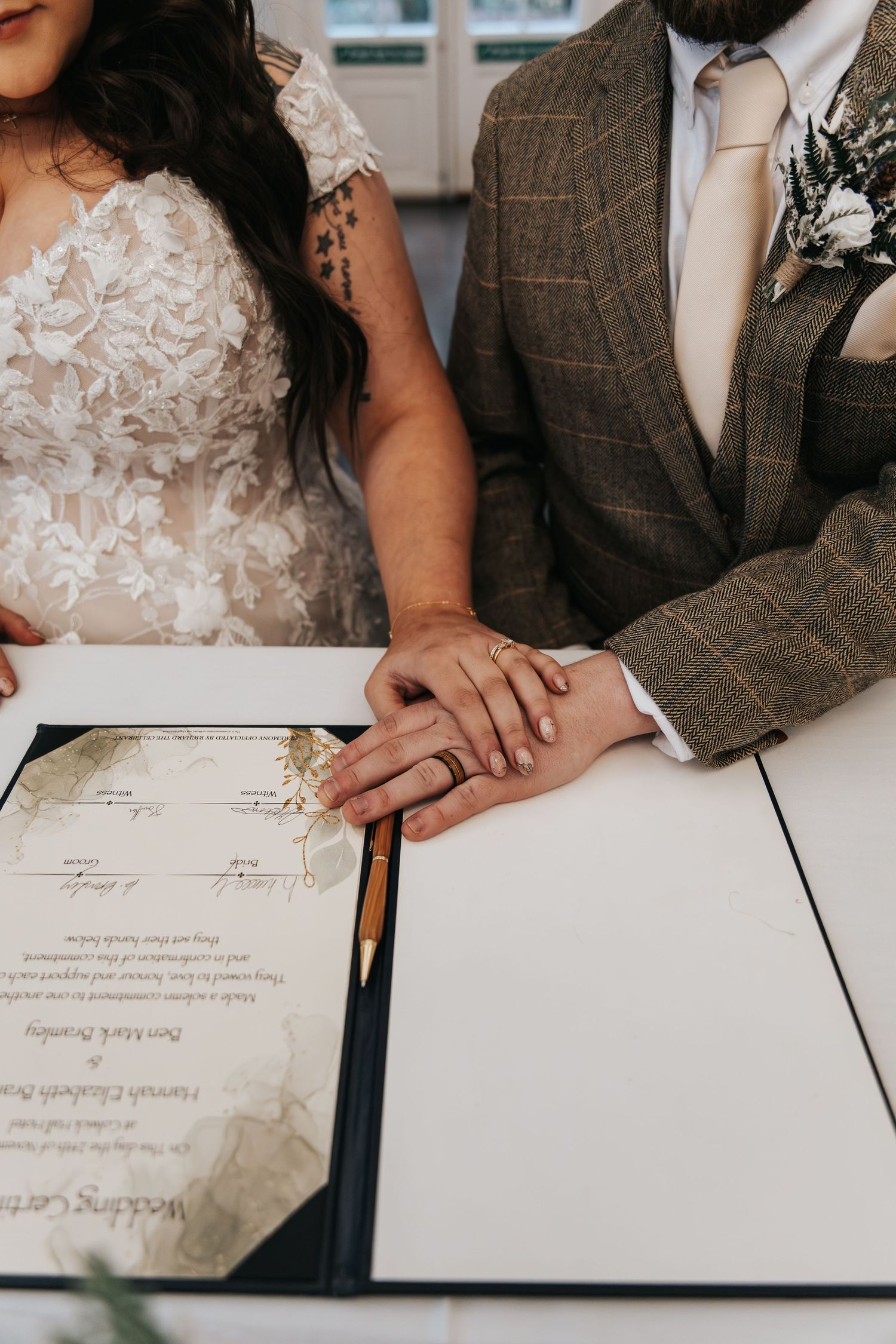 Close-up of couple signing wedding documents together.