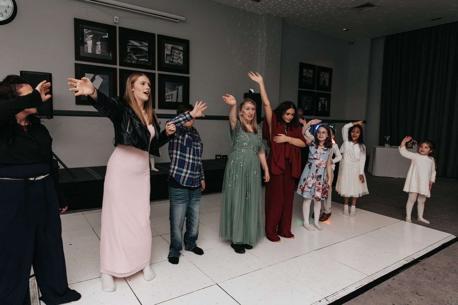 Wedding guests line up on a white dance floor during a reception celebration.