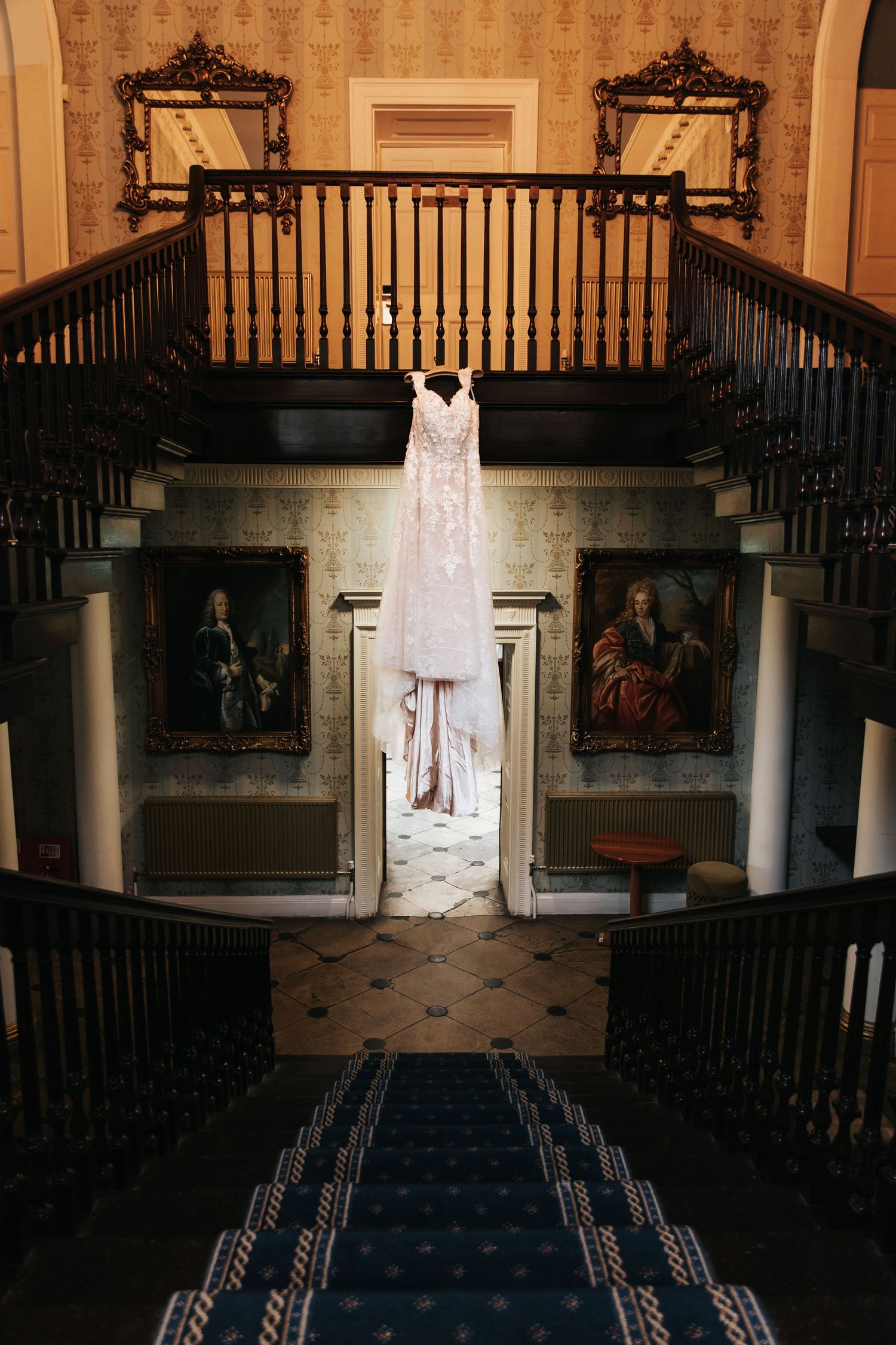 Wedding dress displayed in elegant venue with black railings and classical architecture.