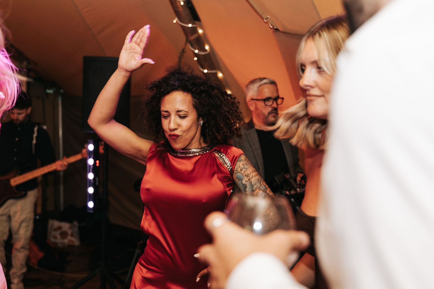 Woman in red dress dancing at a party with fairy lights in the background.