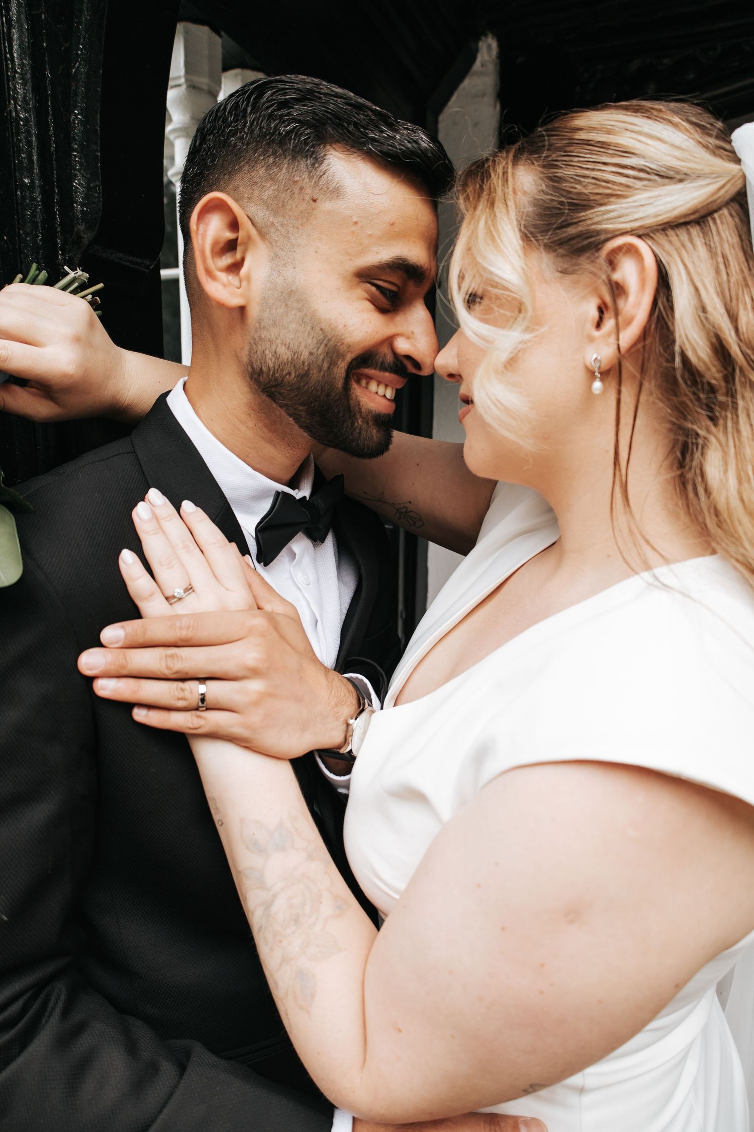 A romantic wedding moment captured between newlyweds in black and white formal attire.