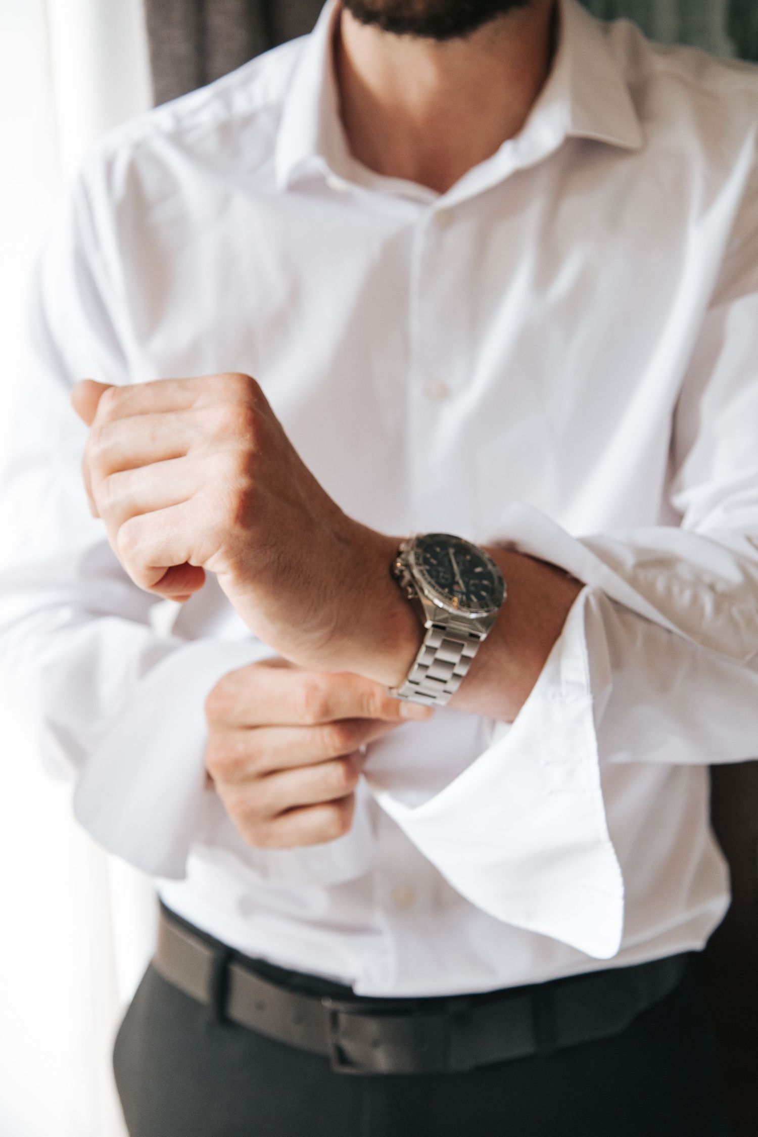 Close-up shots of someone adjusting white dress shirt cuffs and sleeves.