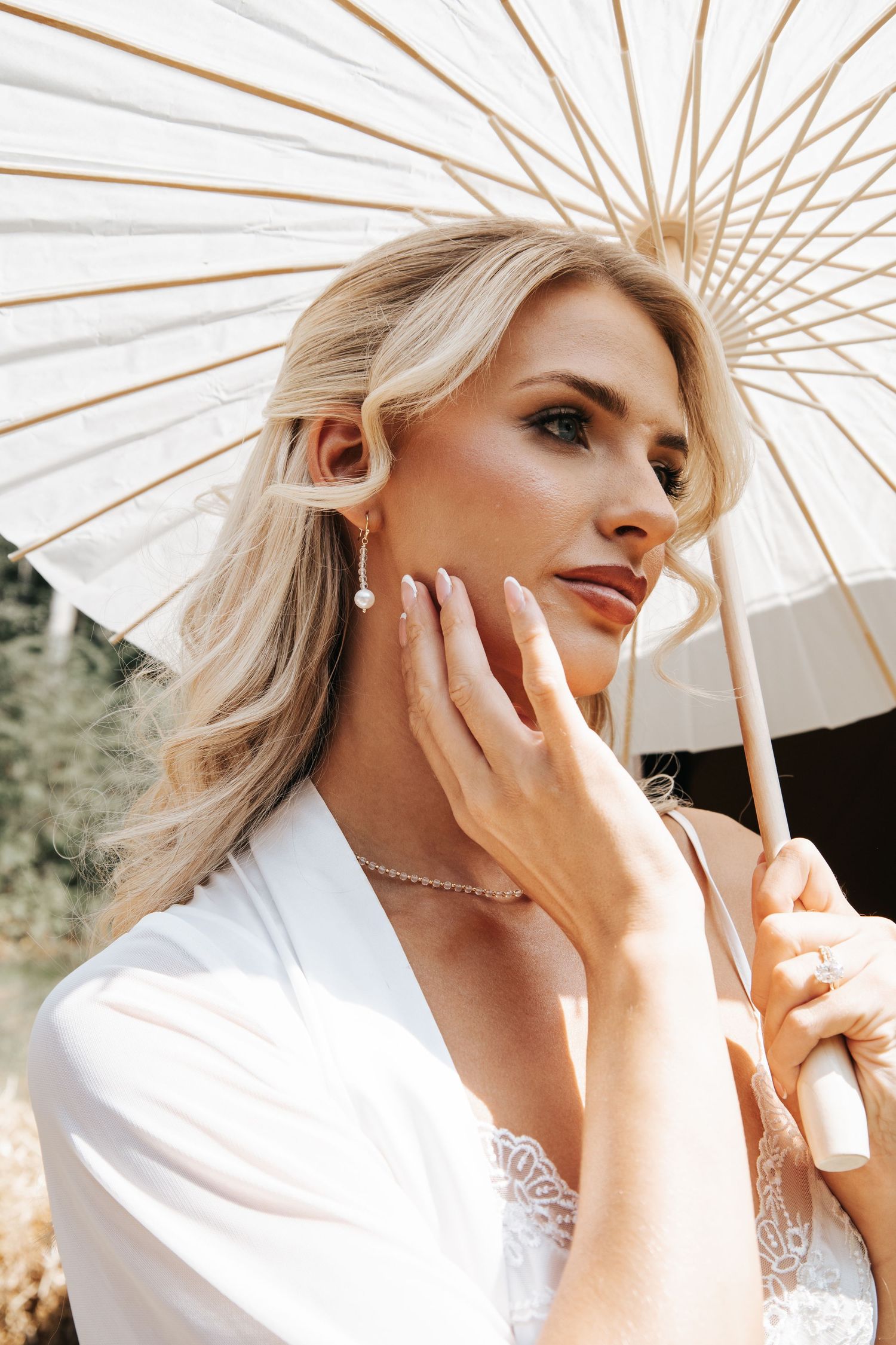 Artistic portrait series with white paper parasol and pearl jewelry details.
