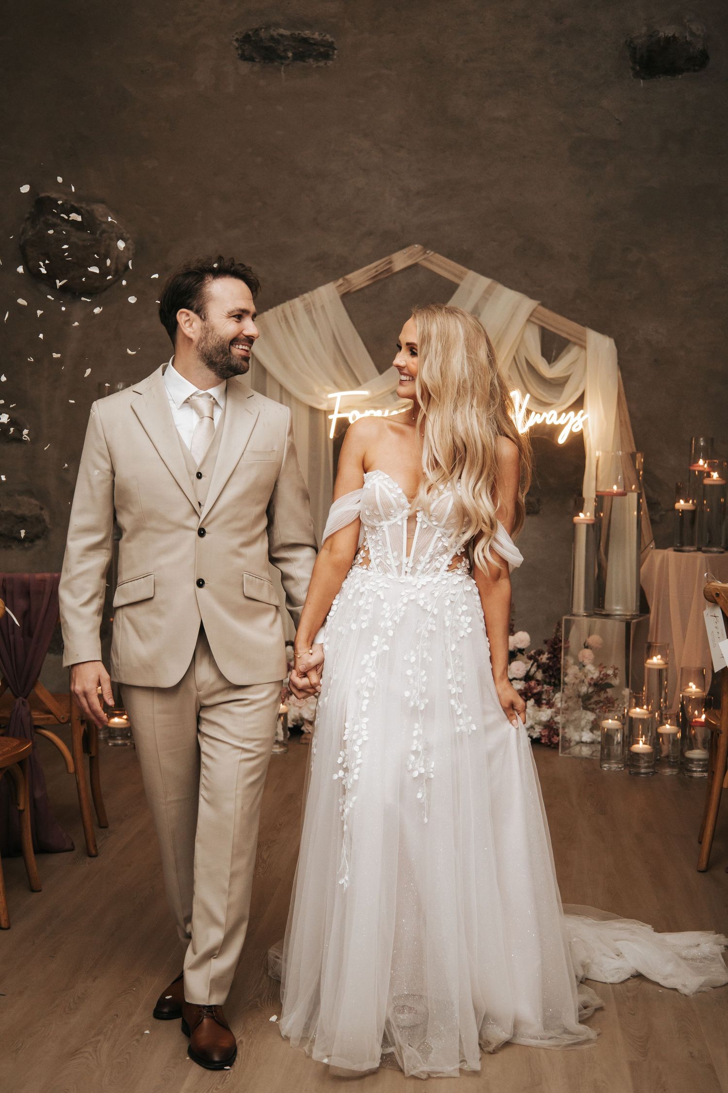 Couple dances in elegantly decorated reception venue with candlelit ambiance.