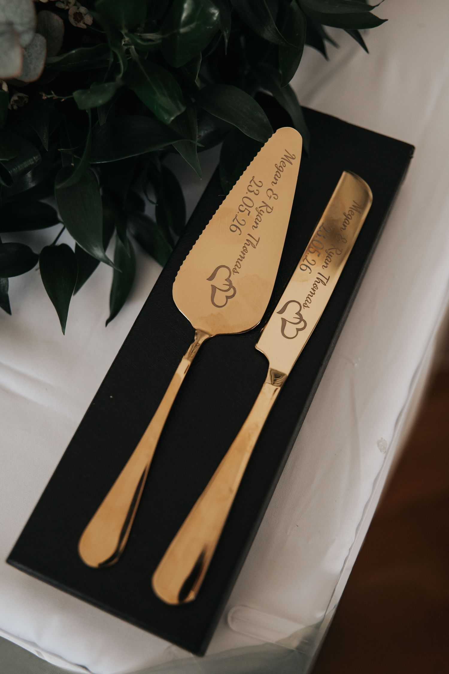 Gold engraved wedding cake server and knife set in black gift box with personalized names and date.