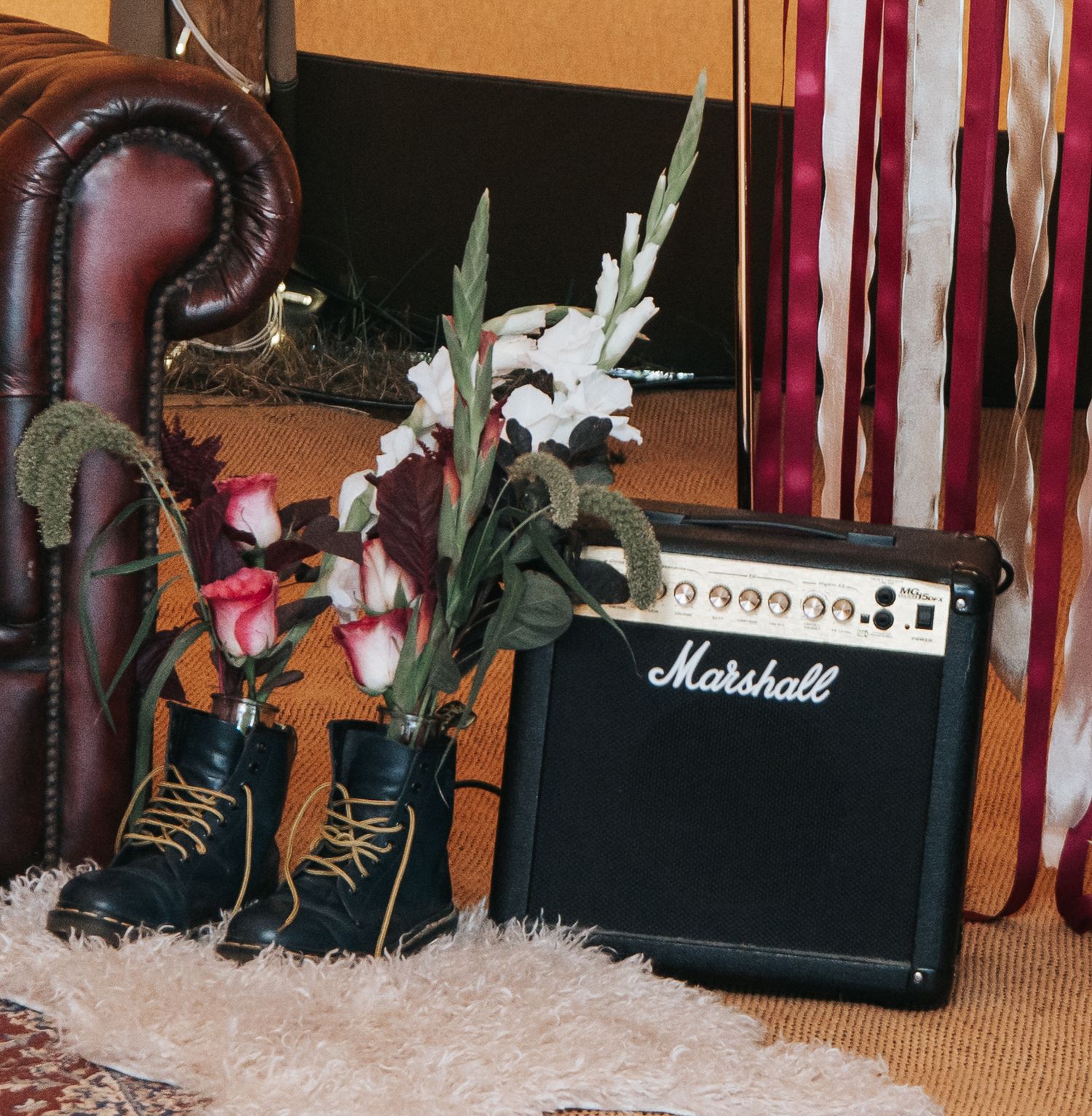 Vintage Marshall amp with combat boots repurposed as a flower vase displaying white gladiolus and pink flowers.