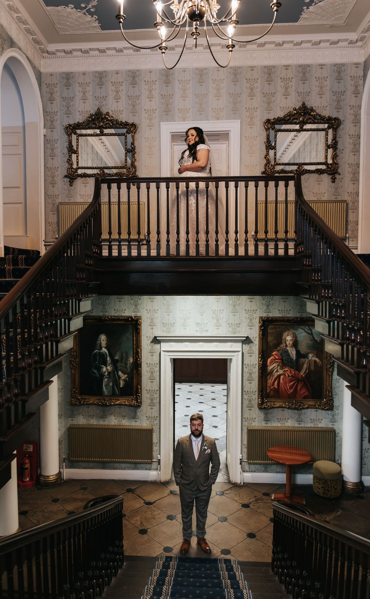 Grand interior of historic venue with ornate staircase and classical artwork on display.