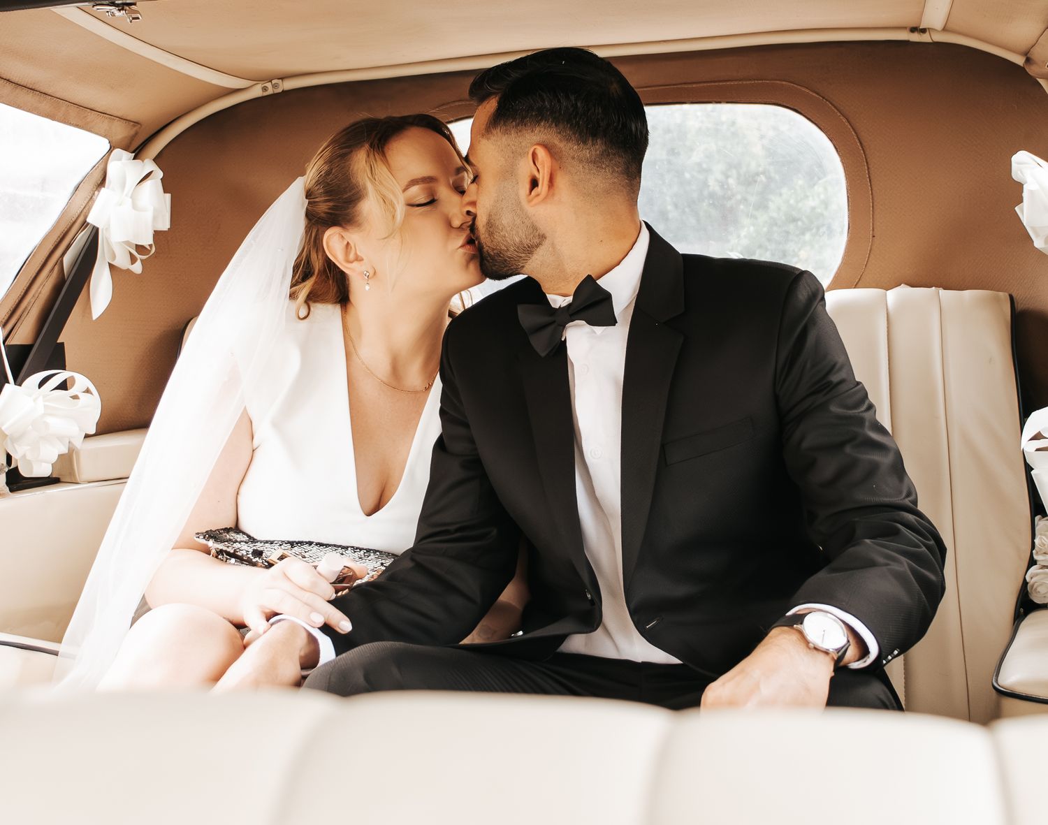Romantic moments captured inside vintage car on wedding day.
