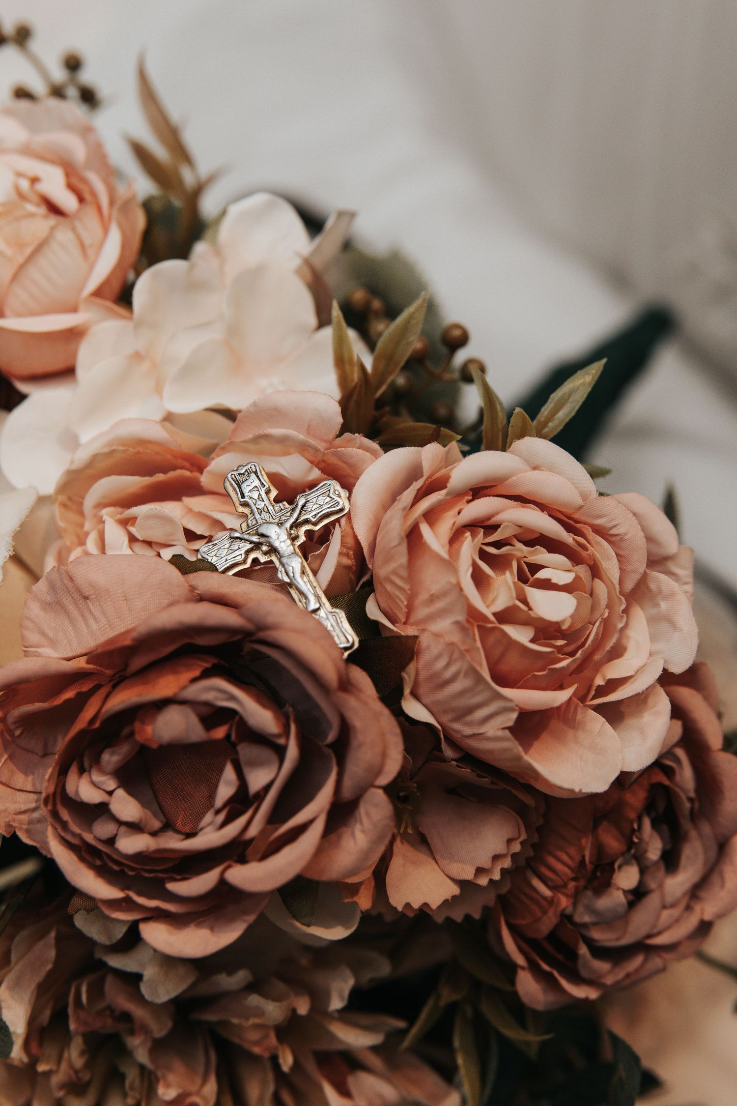 Vintage-style peach roses with a decorative cross detail in a romantic wedding arrangement.