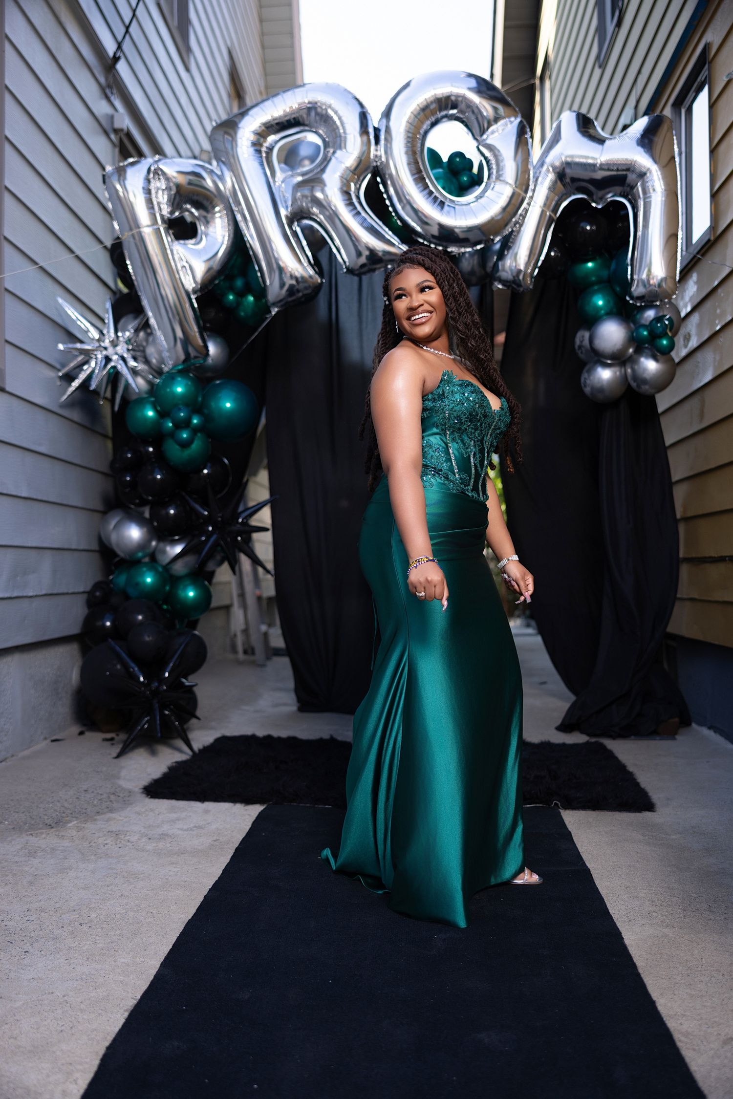 A series of photos showing a person in an emerald green formal dress posing with silver and teal balloon decorations.