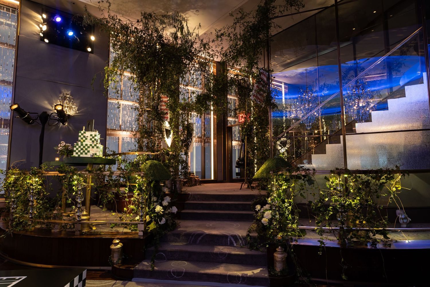 Modern event space decorated with lush greenery and ambient lighting creating a romantic garden-like setting.