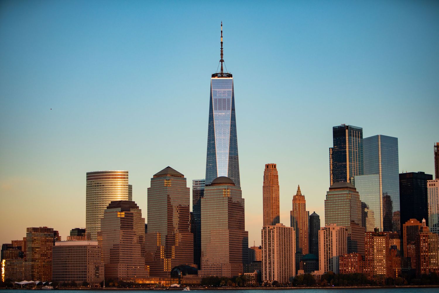 Manhattan skyline panorama with skyscrapers and office buildings at sunset reflecting warm golden light.