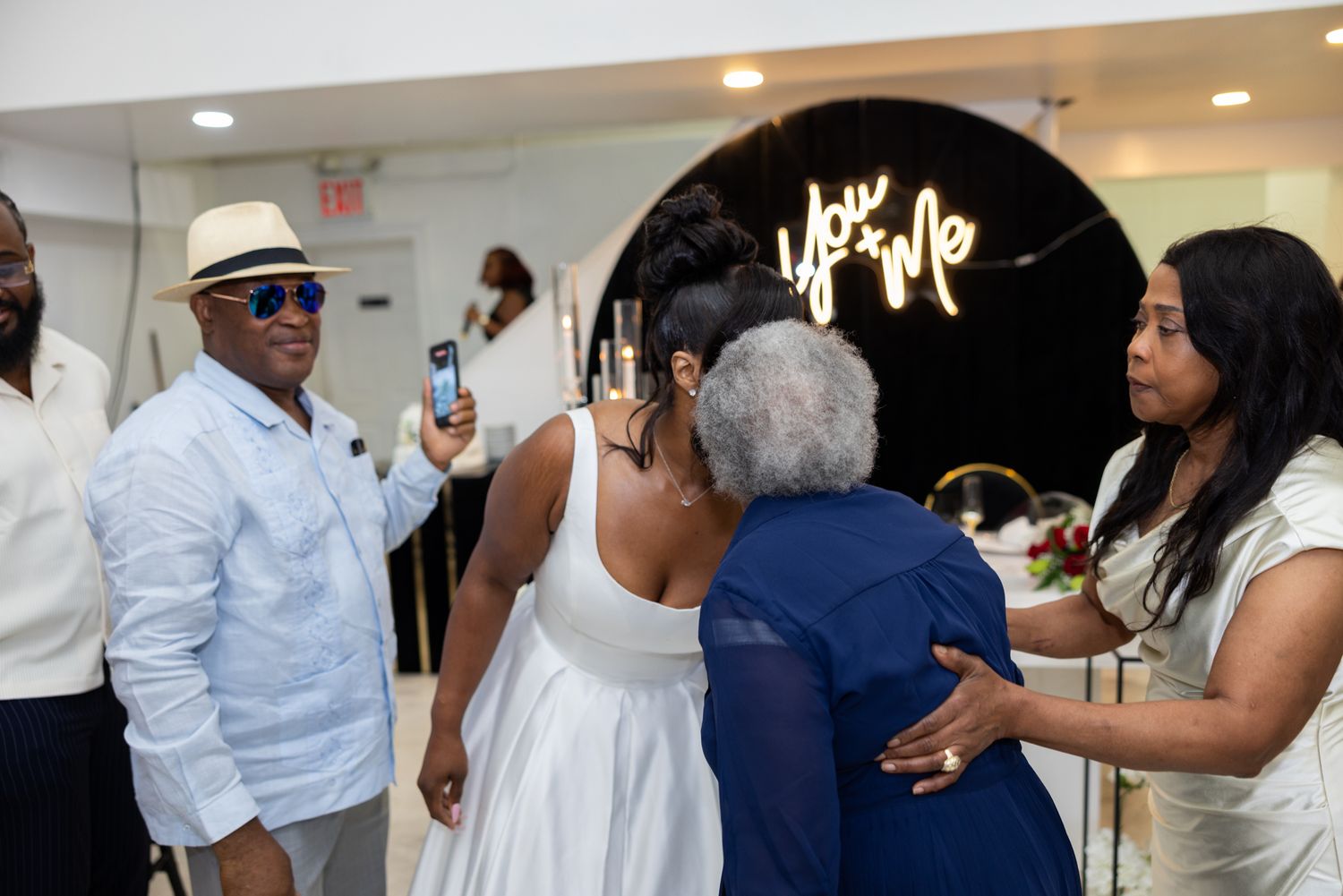 Event guests in formal white attire socialize and network at an elegant indoor gathering.