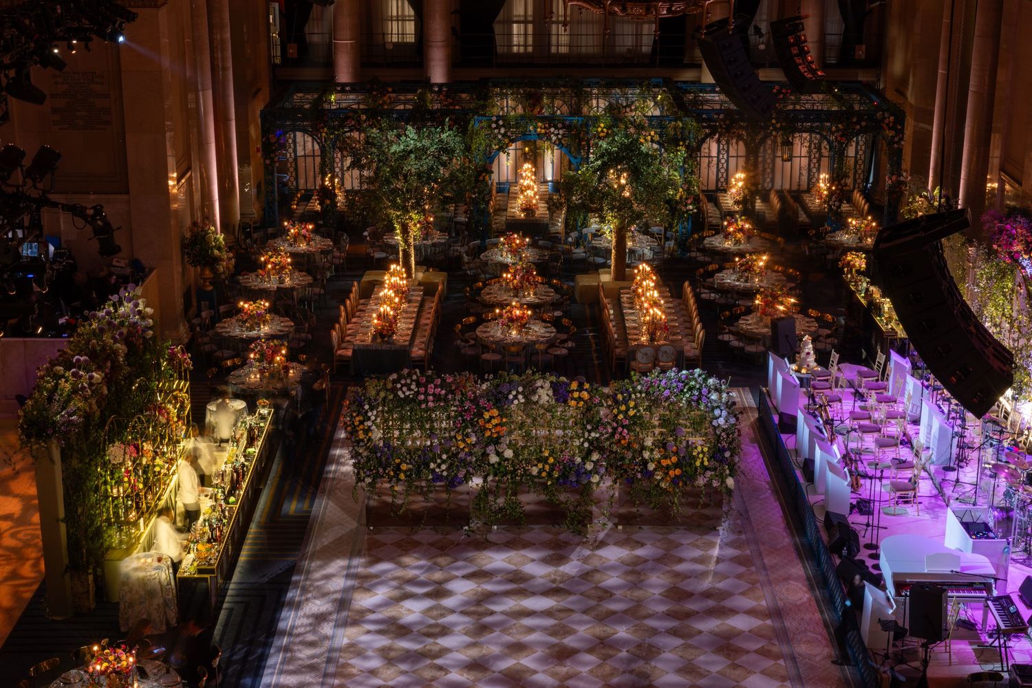 Luxurious event space with illuminated floral arrangements and a checkered dance floor under dramatic lighting.