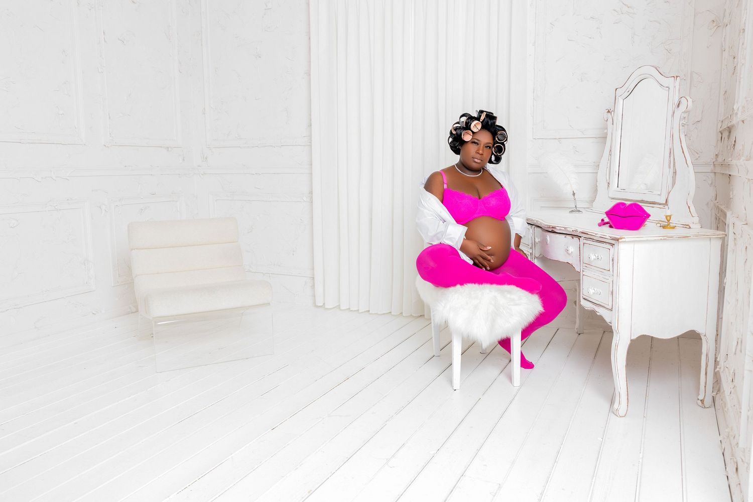 Bright pink accents pop against an all-white modern interior design scheme with elegant furniture and decor.