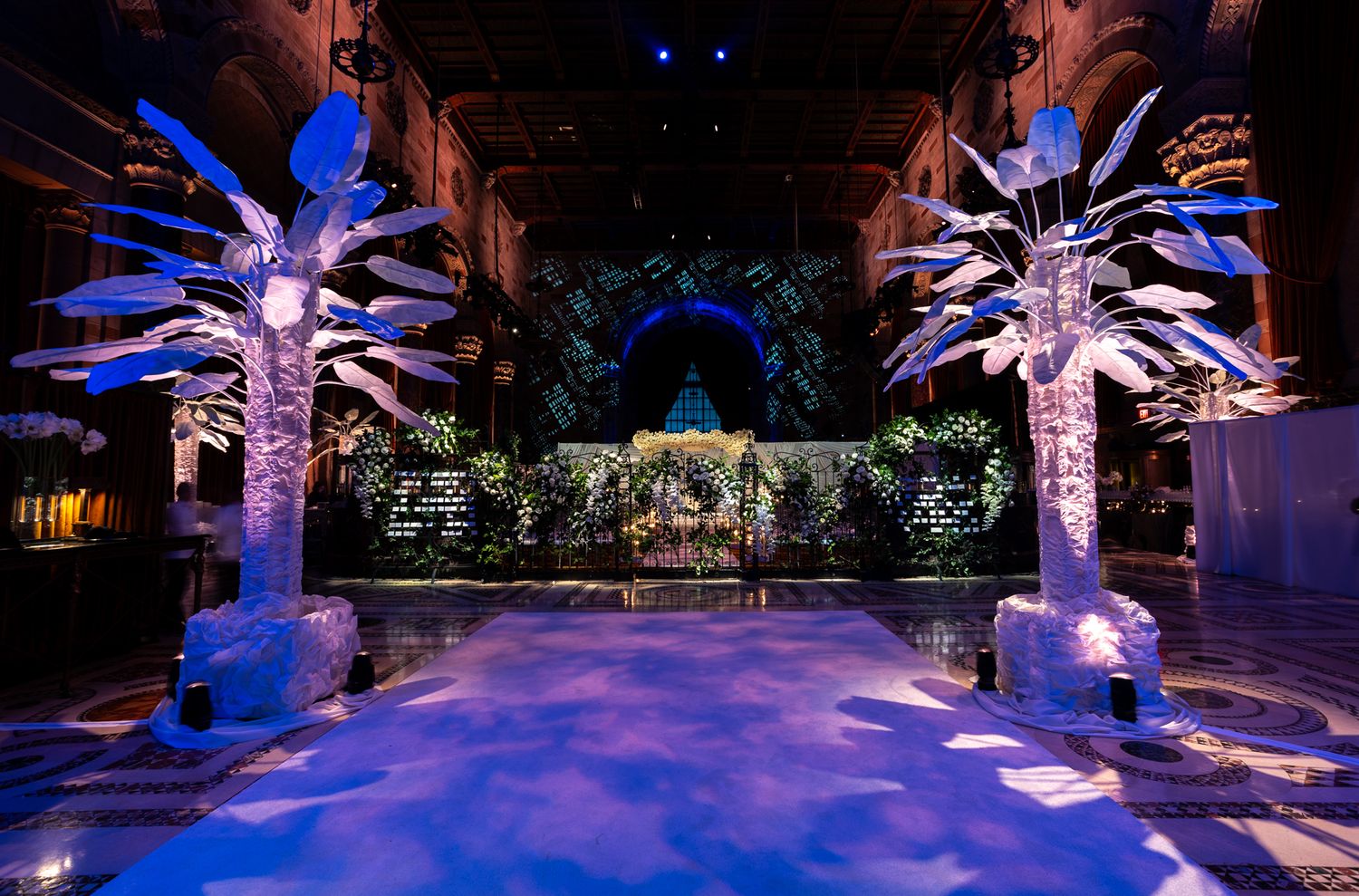 Illuminated outdoor venue with glowing white tree-like structures creating a magical nighttime atmosphere.