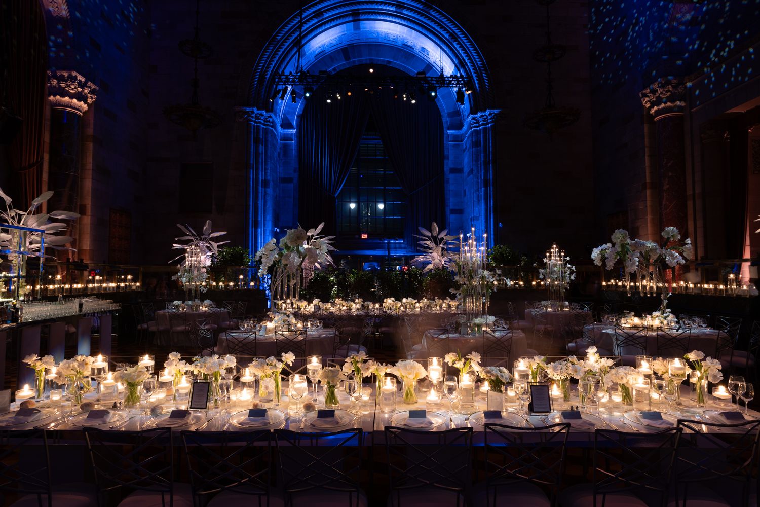 Panoramic view of an elegant wedding reception with candlelit tables and white floral decorations.