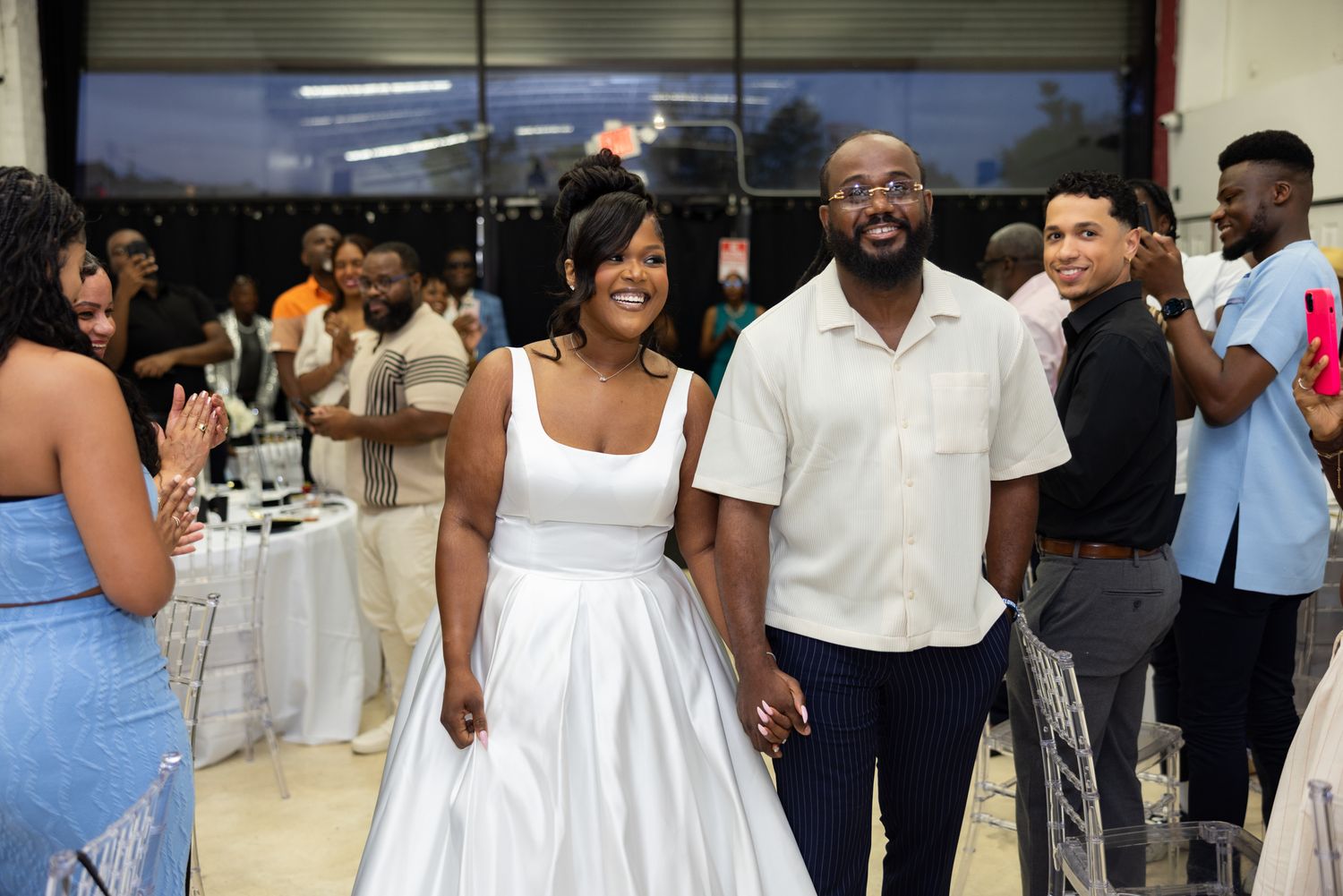 Wedding celebration with guests mingling in a bright indoor venue.